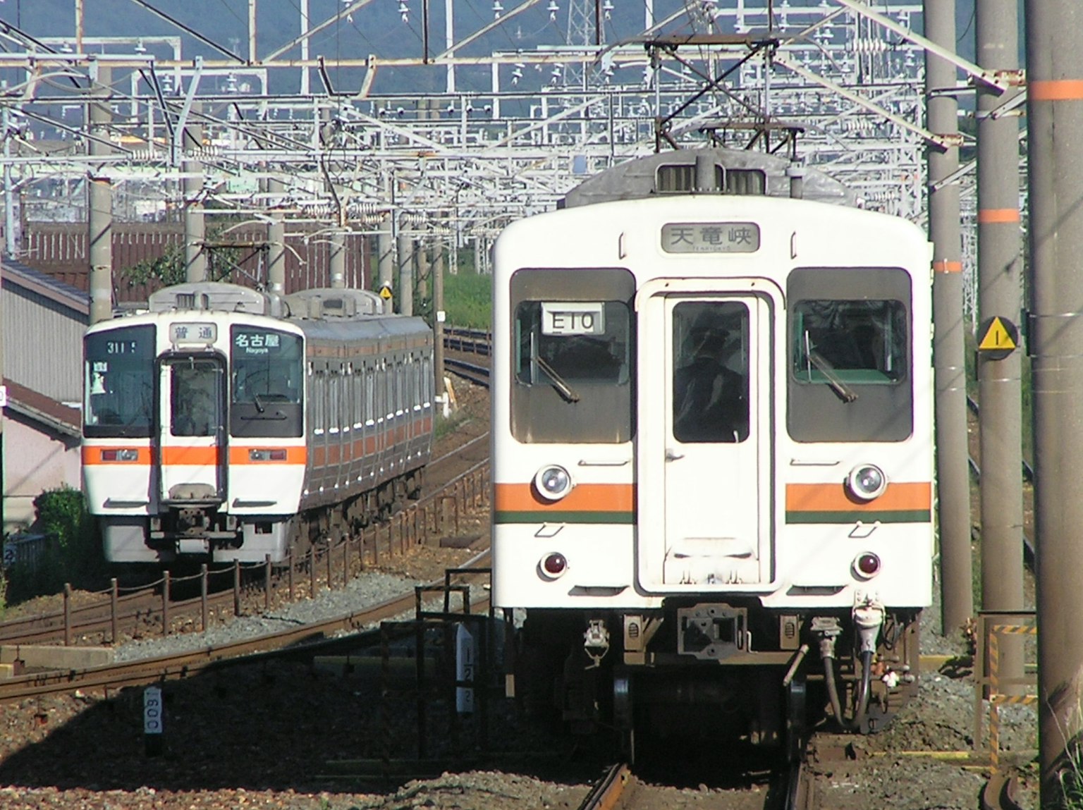 Deux trains sur une voie ferrée avec des lignes électriques aériennes