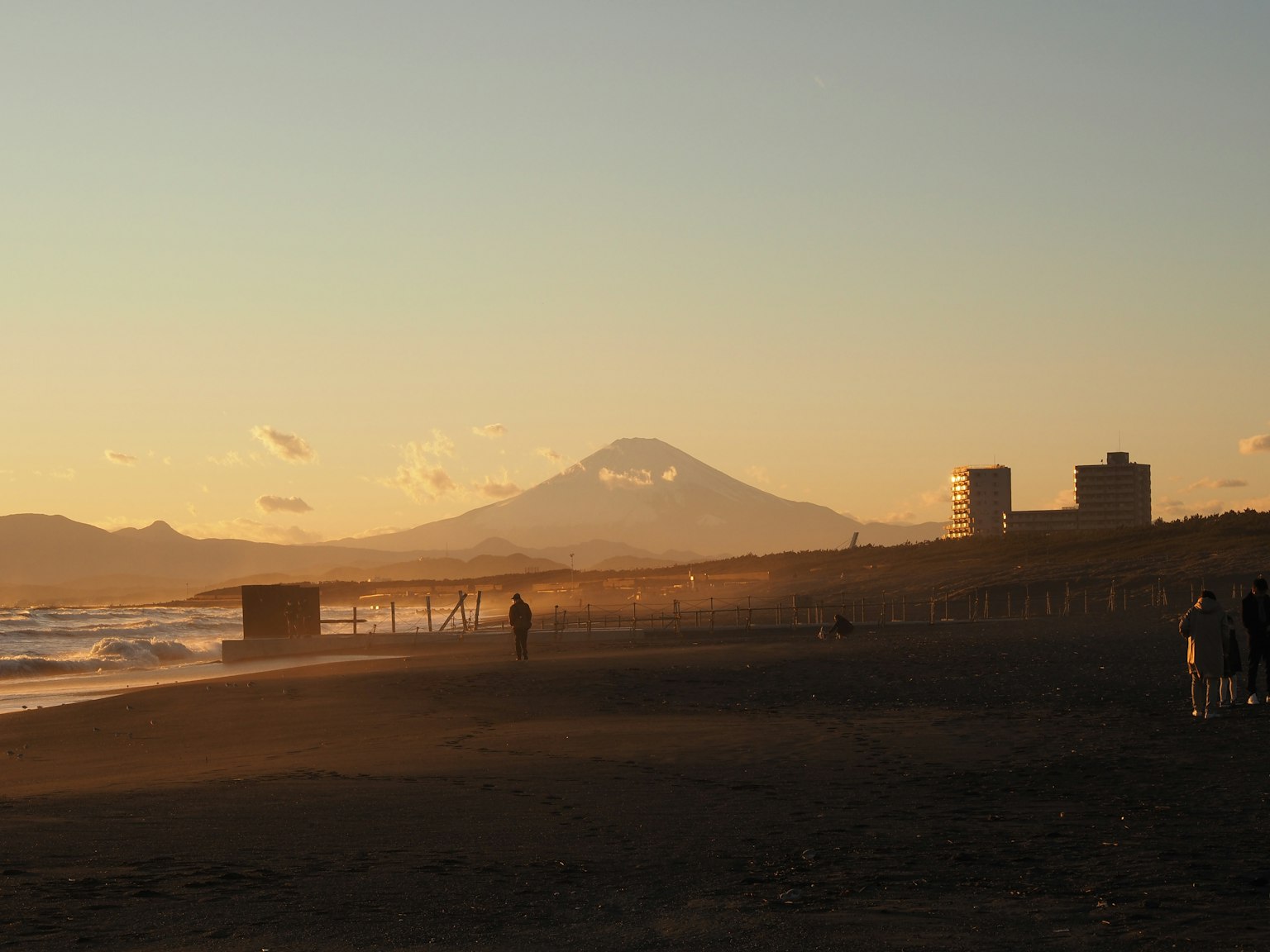 ทิวทัศน์ชายหาดยามพระอาทิตย์ตกพร้อมภูเขาฟูจิในพื้นหลัง