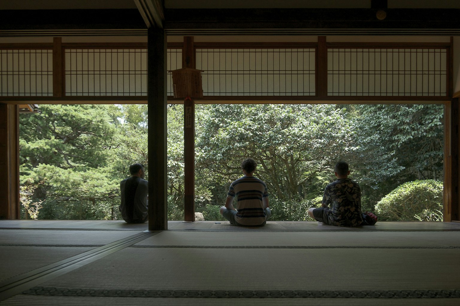 三个人坐在传统日本房间里俯瞰宁静的花园