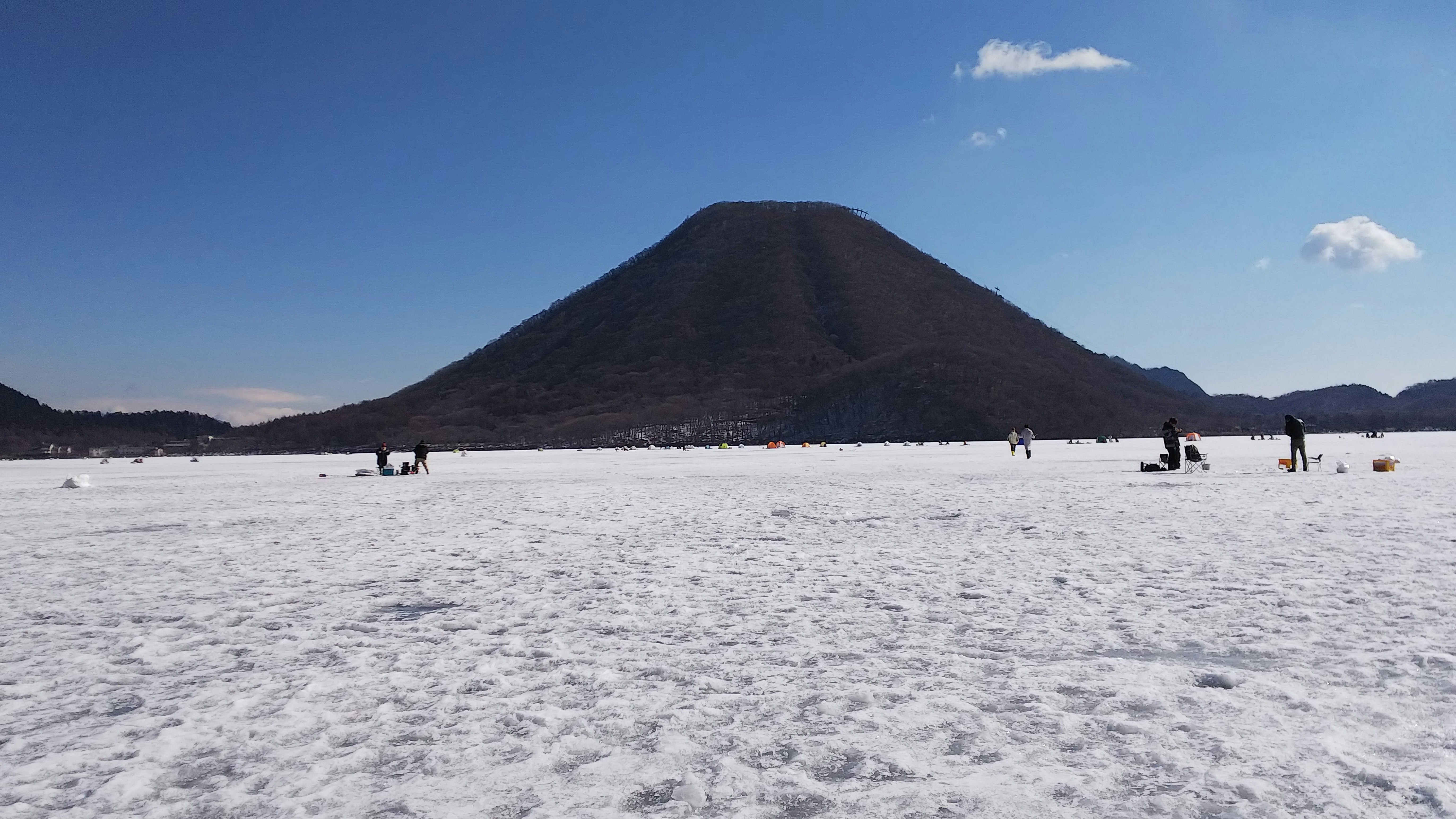 榛名富士と榛名湖の氷上でワカサギ釣りをする人々の風景
