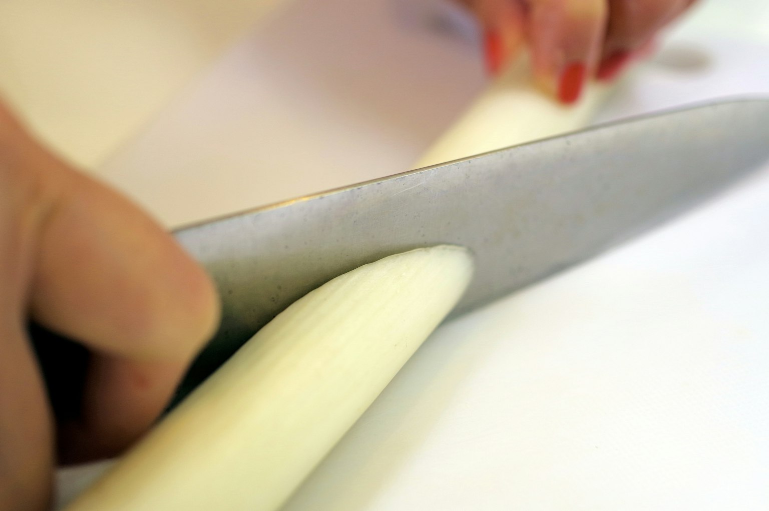 Una mano cortando un vegetal blanco con un cuchillo