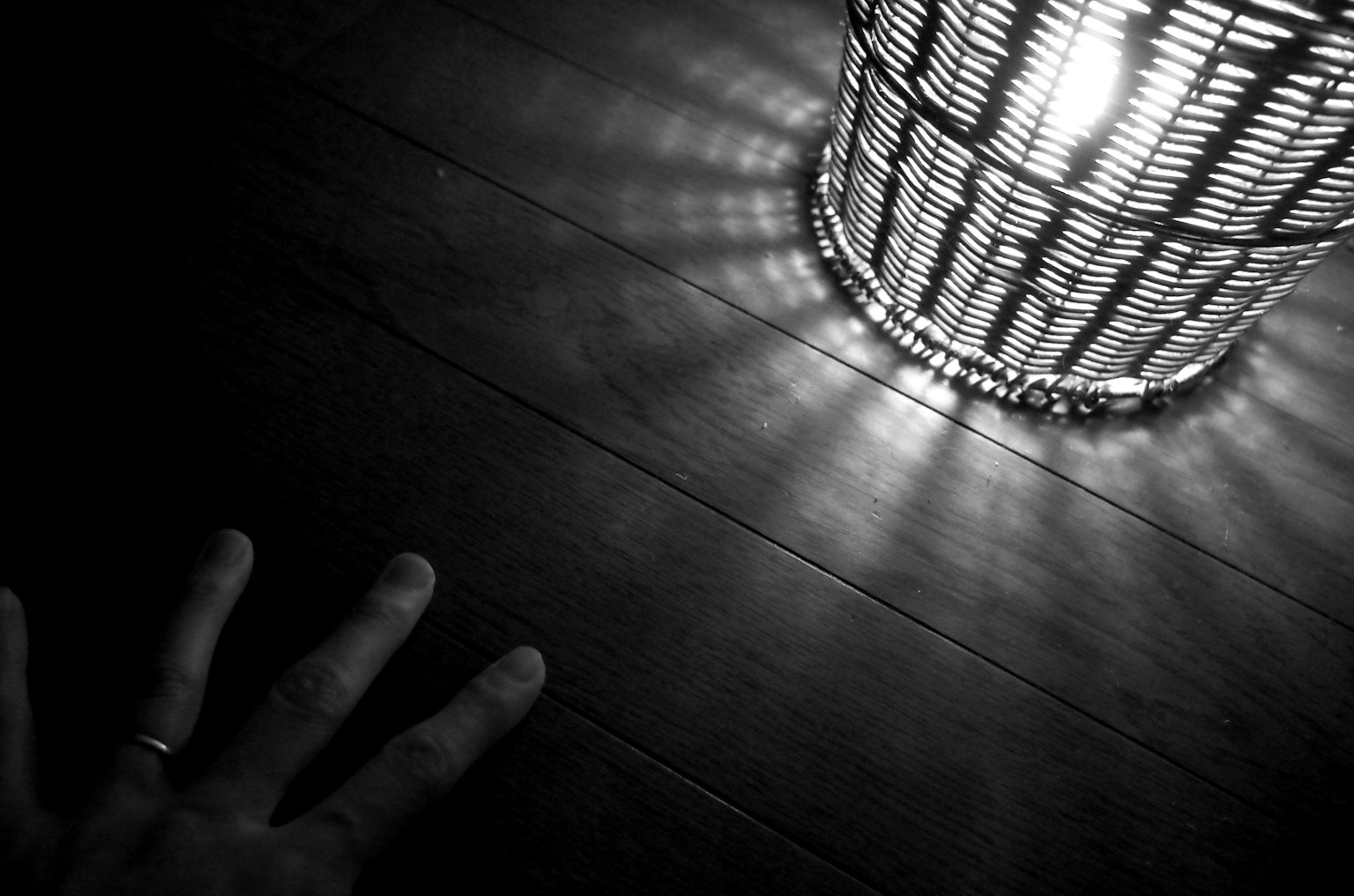 Image en noir et blanc d'une main atteignant une lampe lumineuse