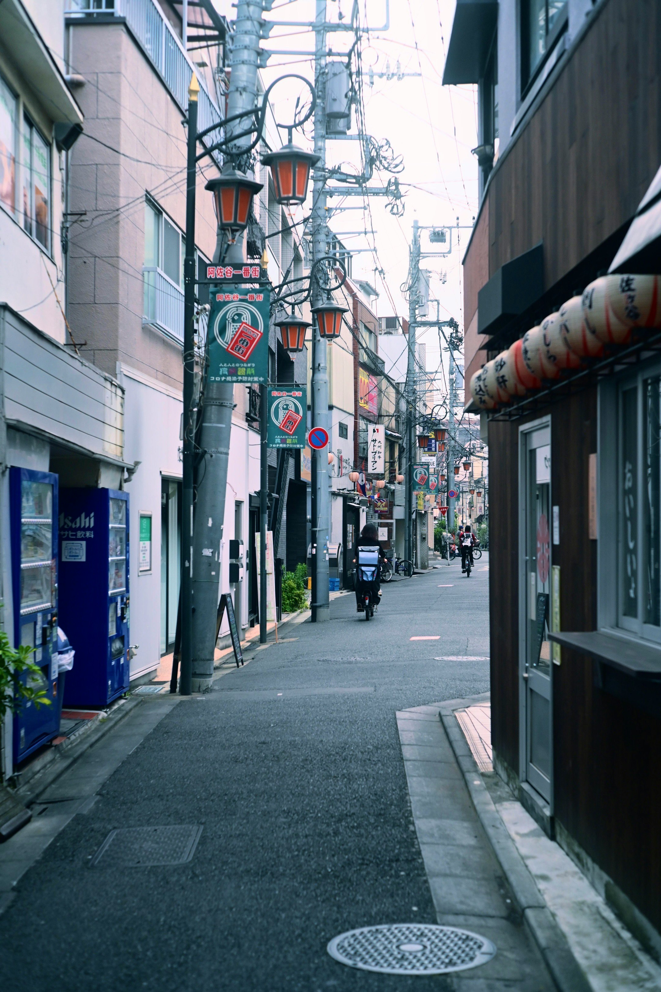 路地に並ぶ看板と街灯のある商店街の通り