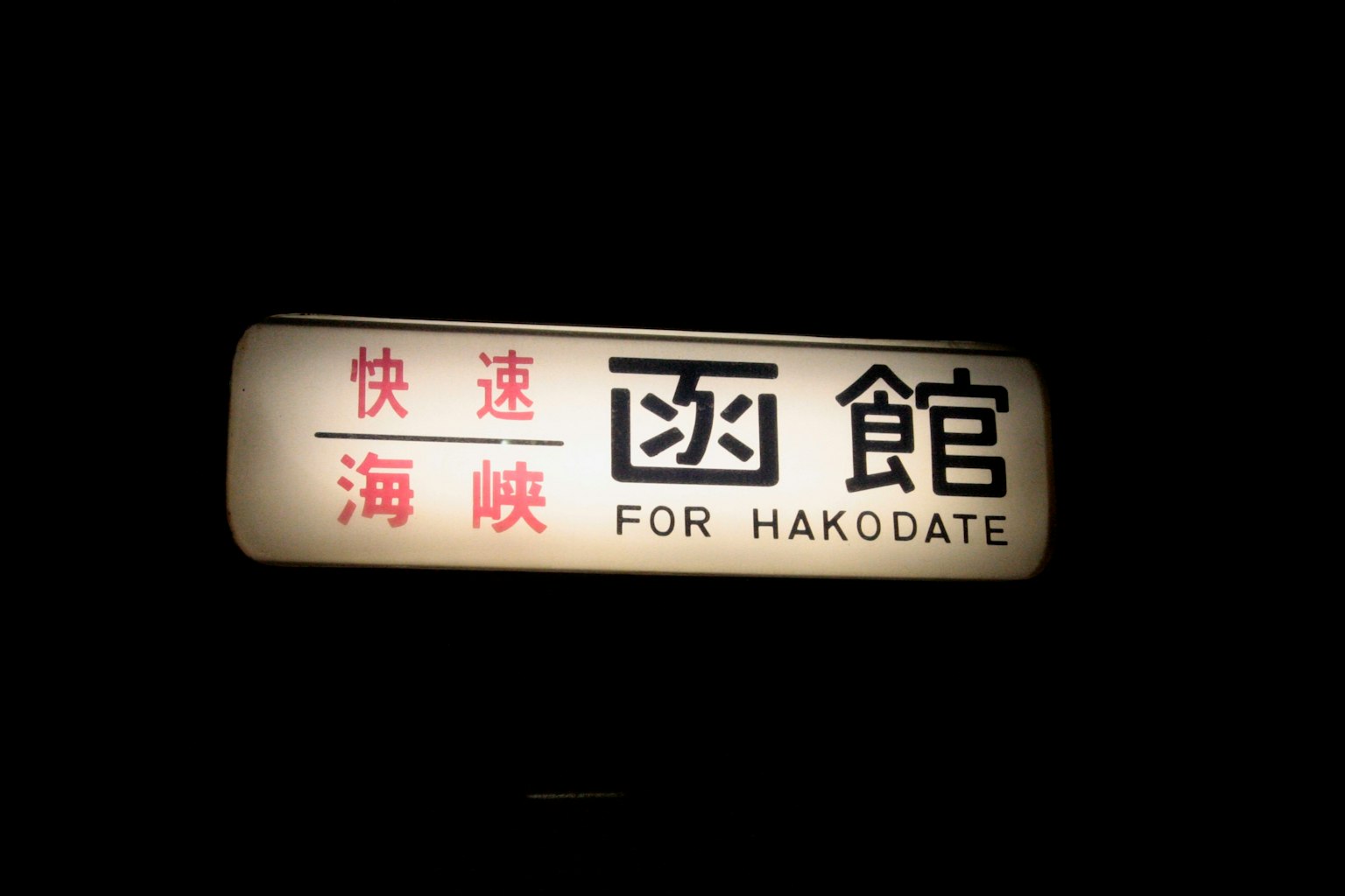 Panneau pour Hakodate avec des lettres rouges proéminentes dans un cadre sombre