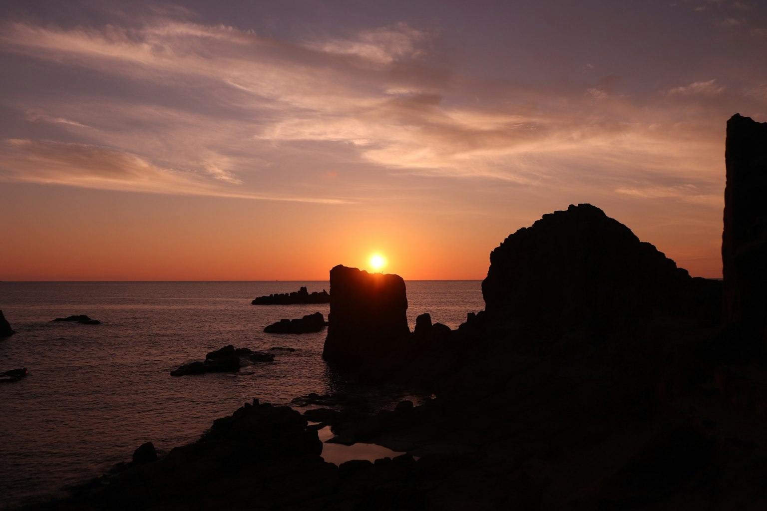 Seaside landscape with sunset behind rocks