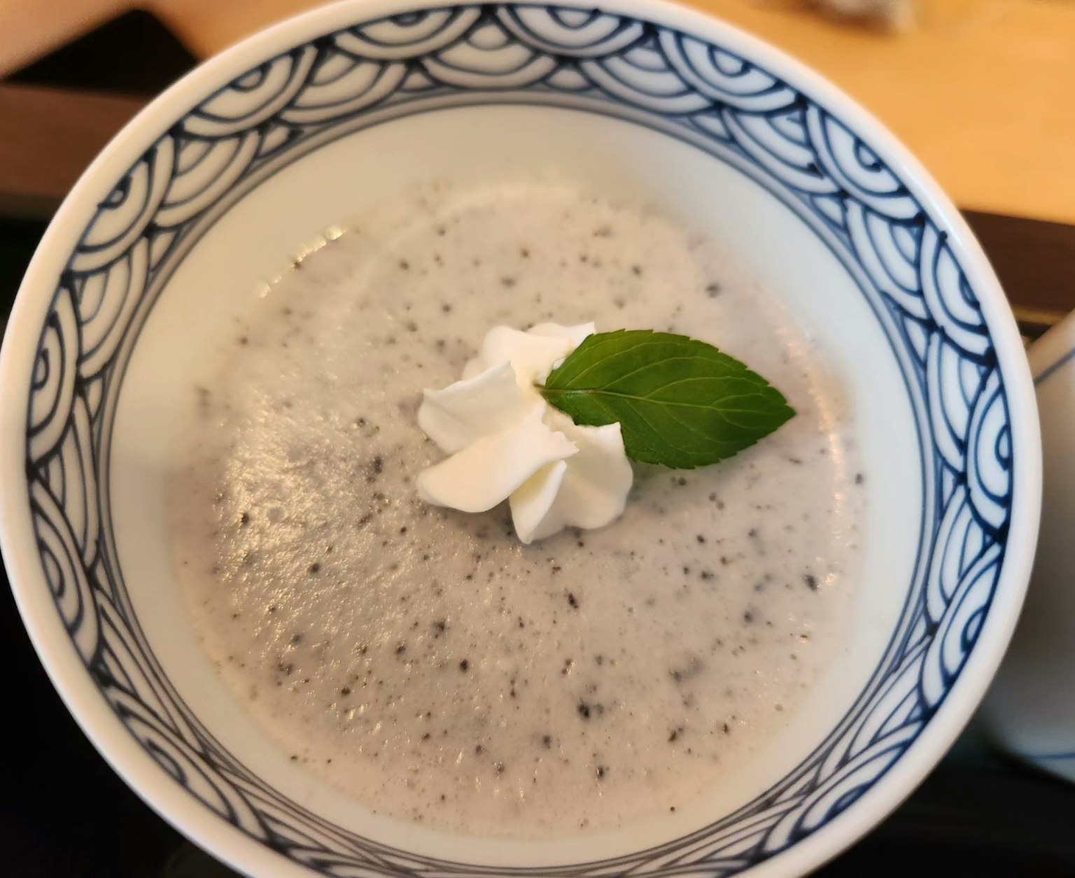 Dessert cremoso bianco guarnito con foglia di menta e panna montata in una ciotola in stile giapponese