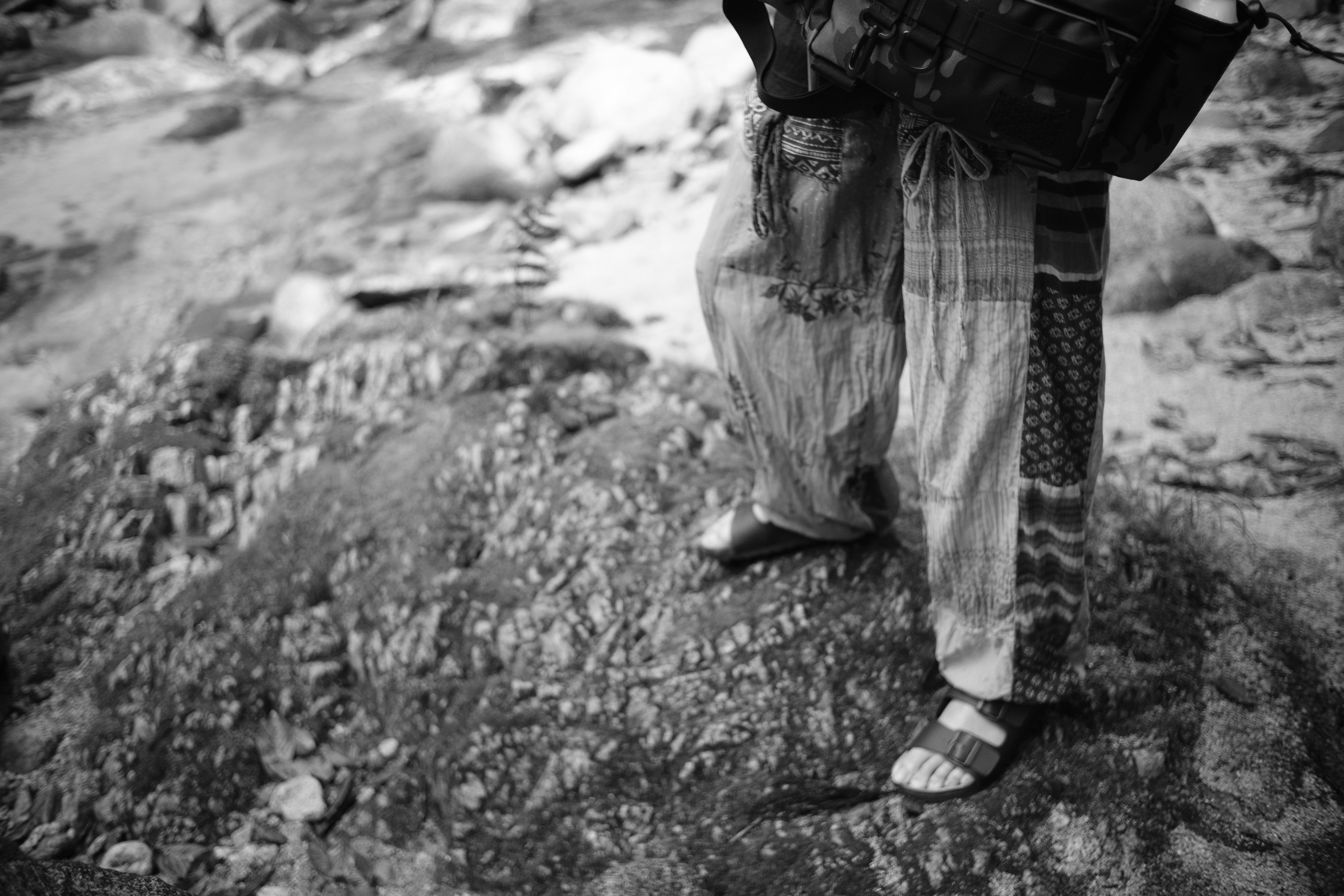 person standing on a rocky ground with a camera bag