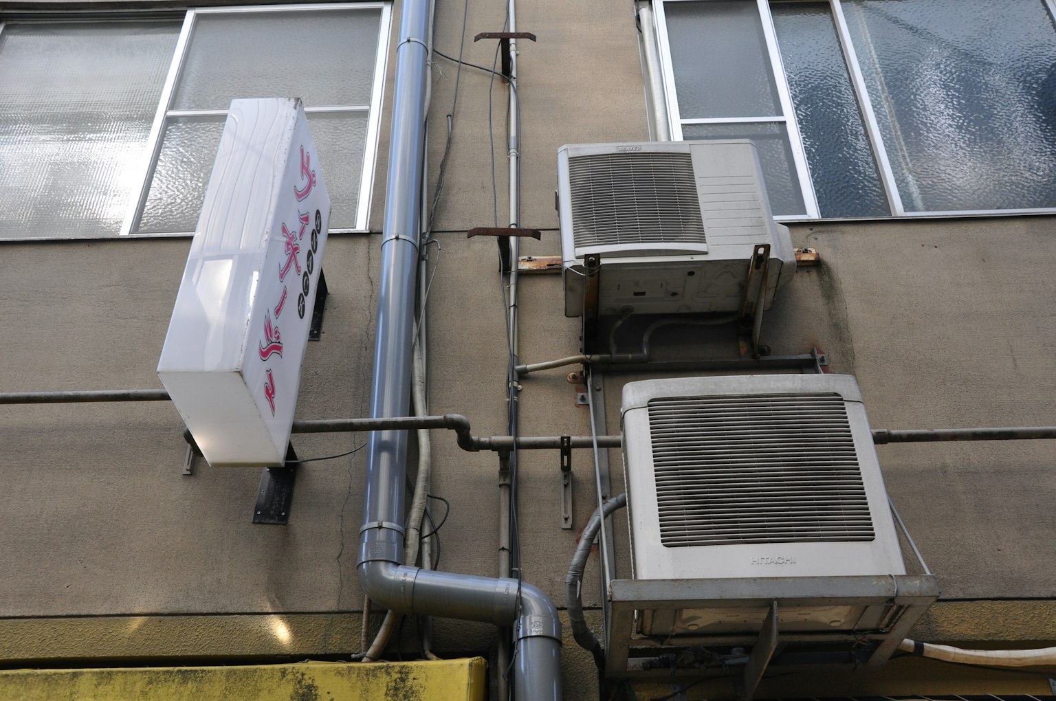 Image d'unités de climatisation montées sur un mur extérieur avec un panneau