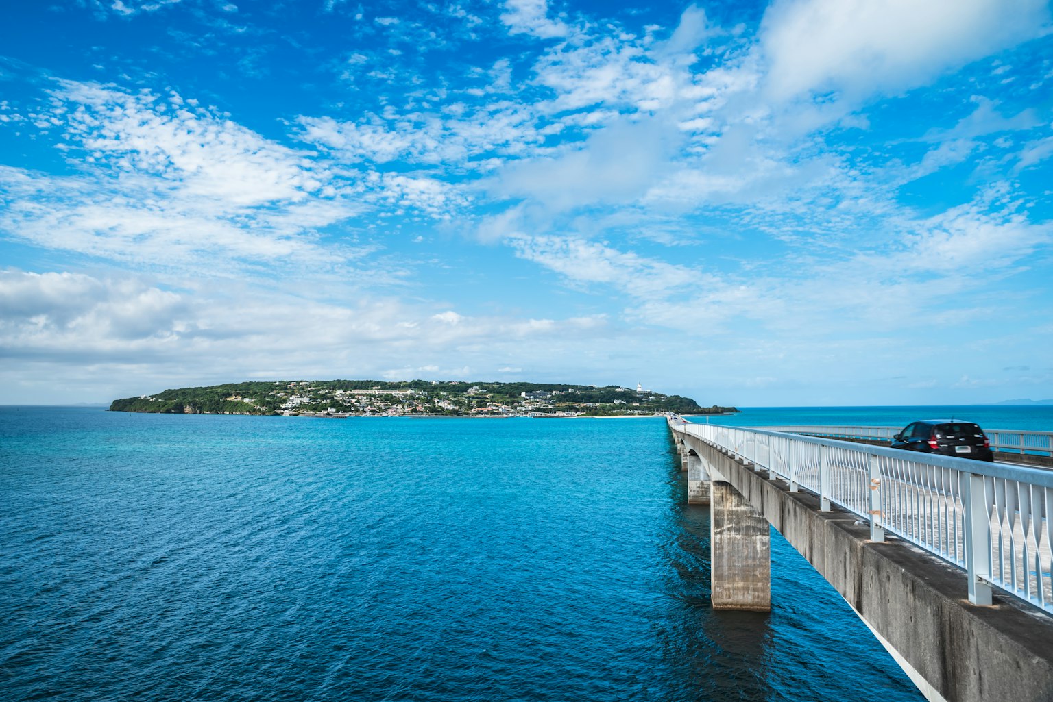 Una vista escénica de un puente que se extiende en aguas turquesas con una isla al fondo