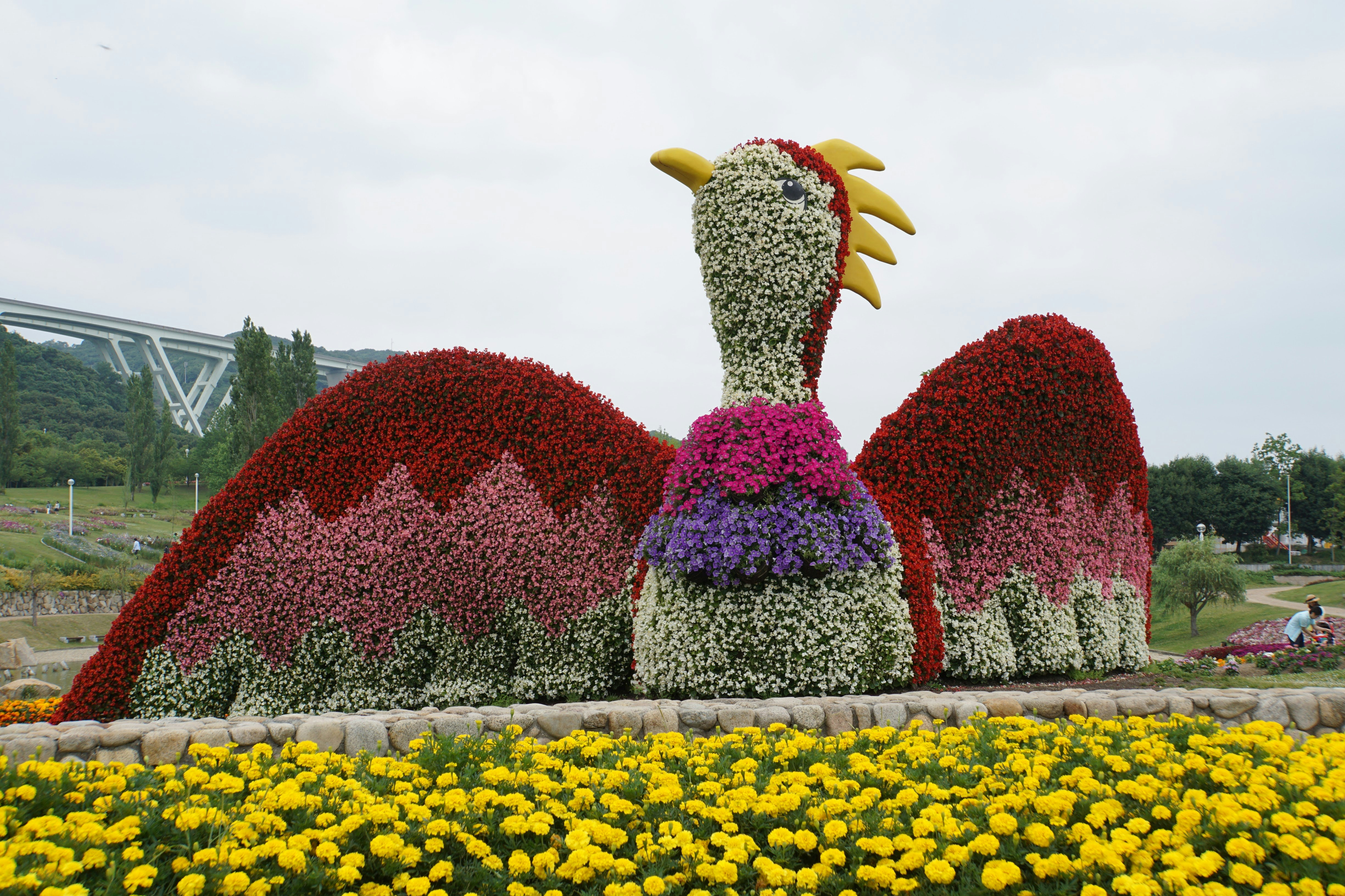 scultura di uccello fatta di fiori in un’aiuola di fiori gialli