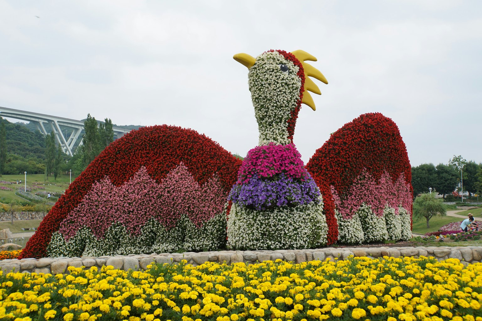 Large bird sculpture made of colorful flowers in a garden