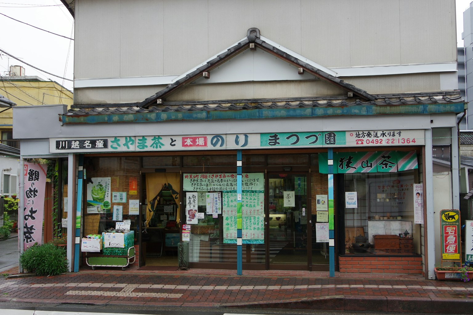Äußere eines traditionellen japanischen Gebäudes mit Beschilderung und umliegenden grünen Pflanzen