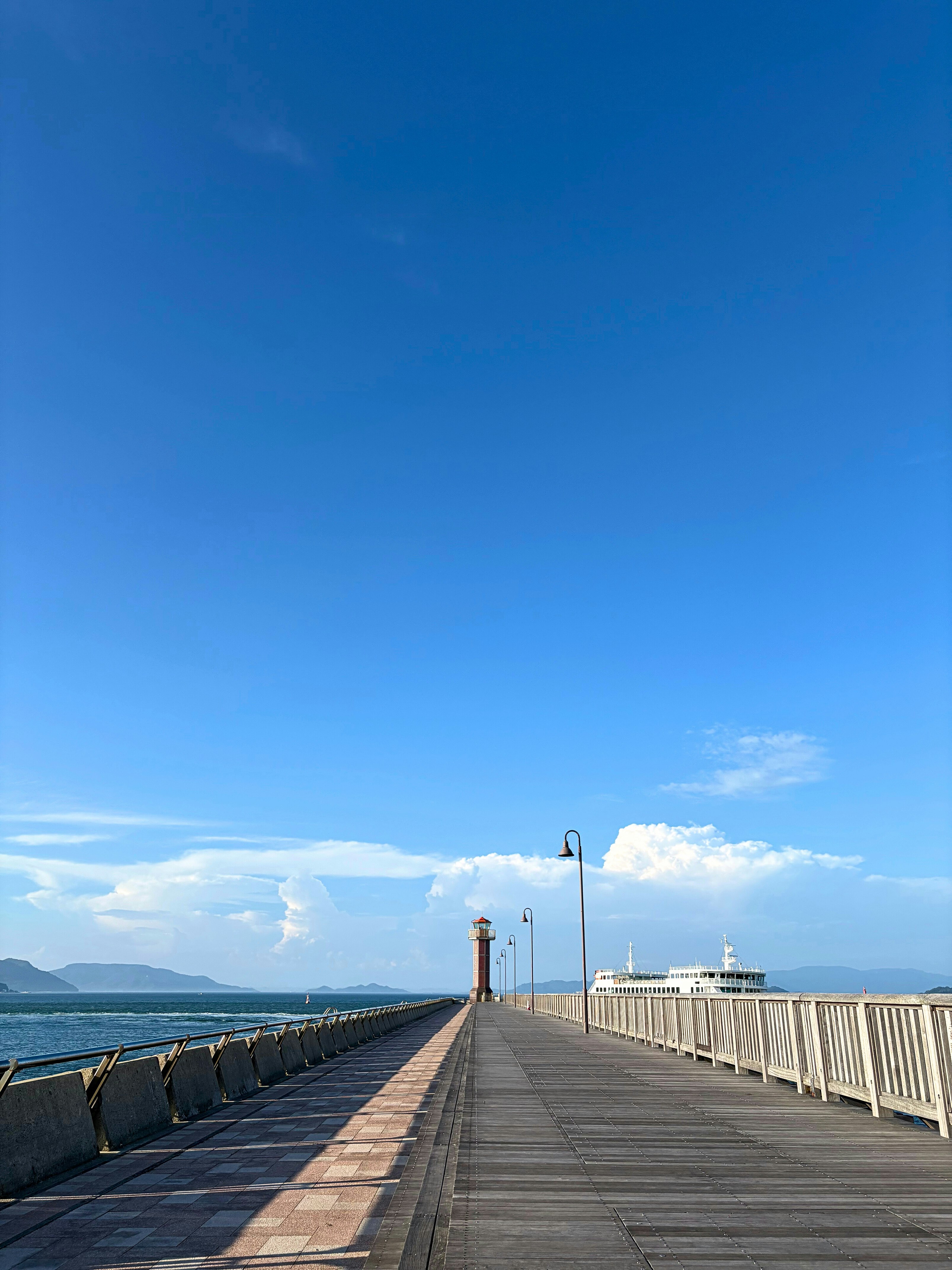 瀬戸内海を望む赤灯台のある海辺の桟橋