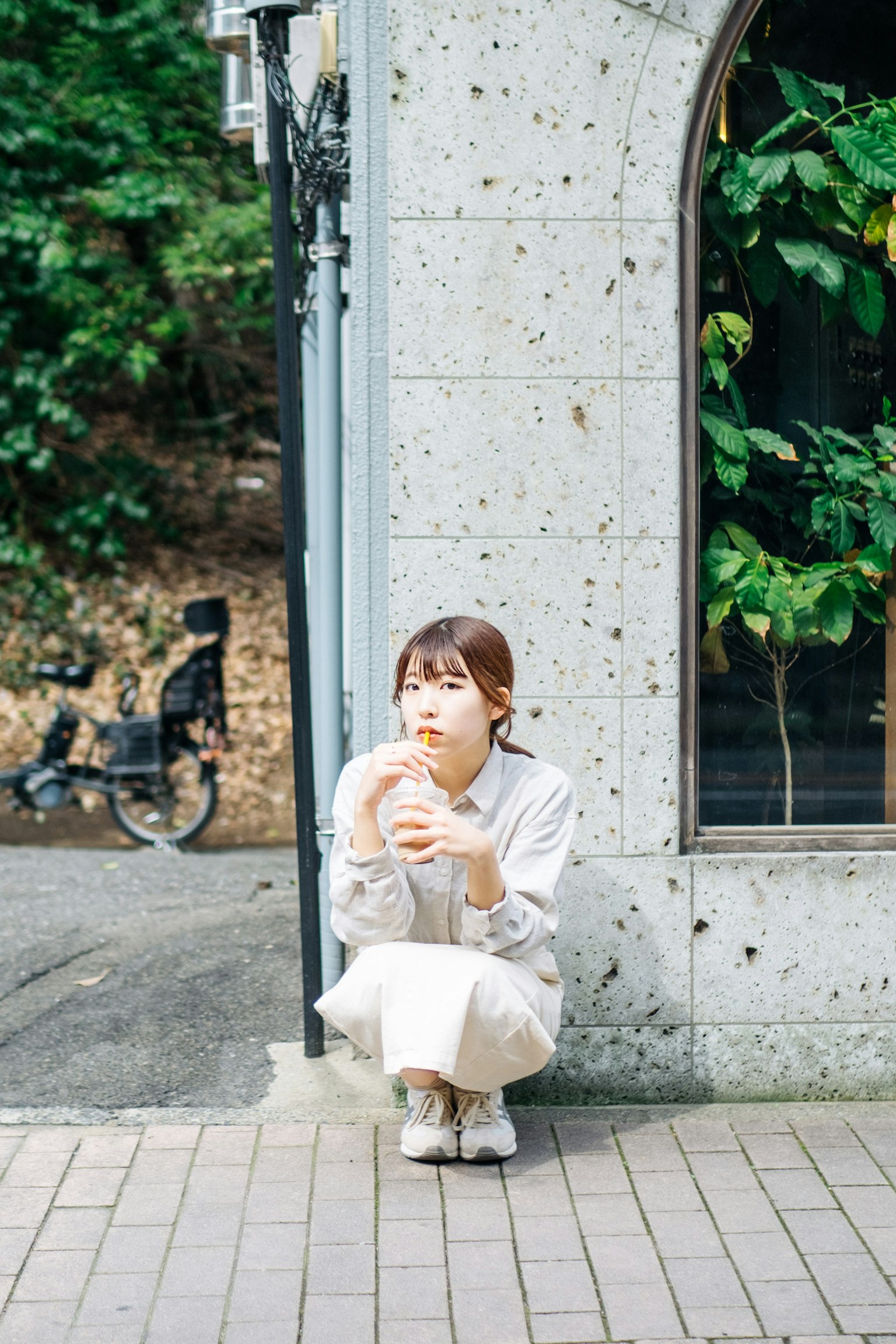 女性坐在街角，手里拿着咖啡杯