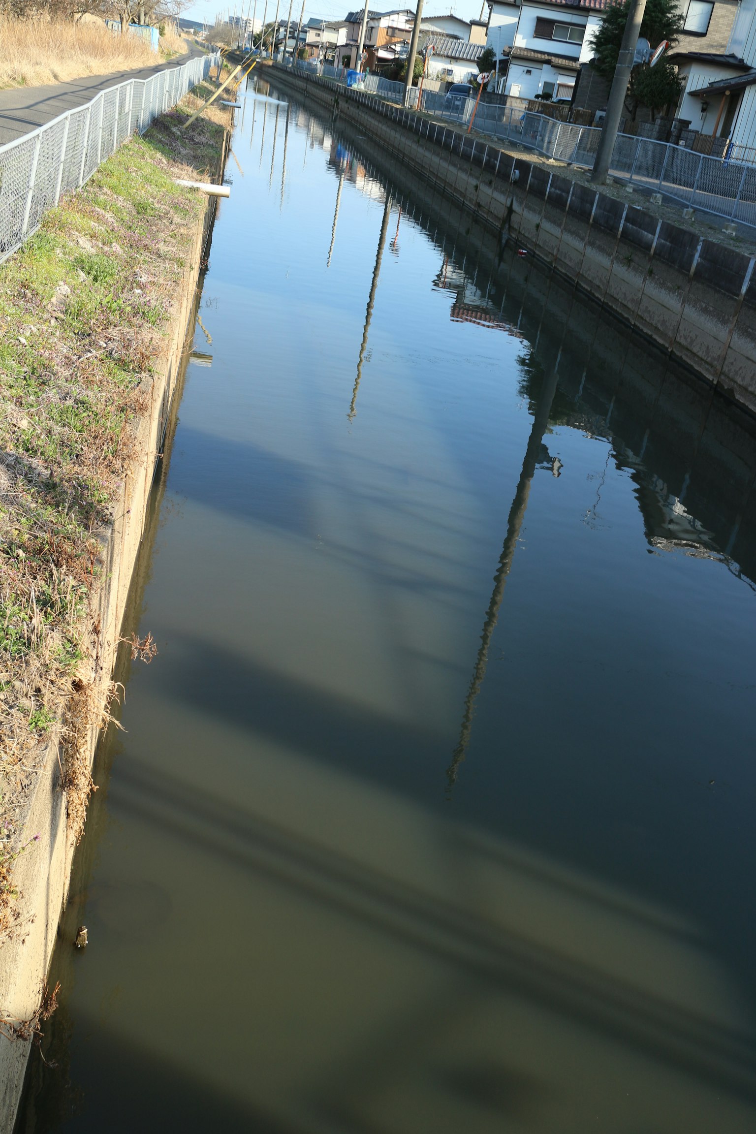 Calm canal water reflecting surrounding scenery and buildings