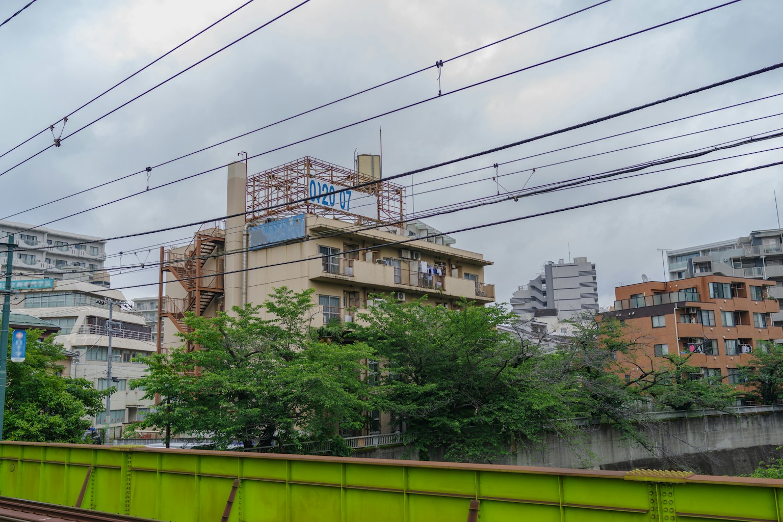 Vista di un edificio e alberi vicino a una recinzione verde e binari