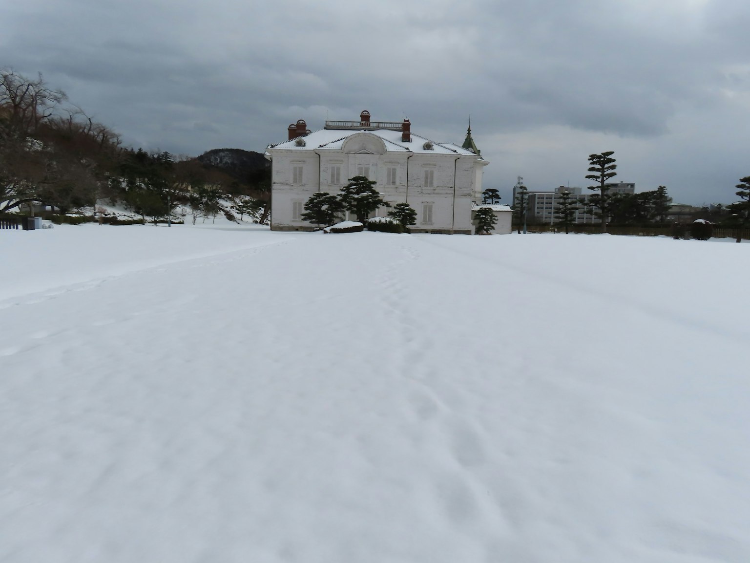 Ein weißes Gebäude auf einem verschneiten Feld unter einem bewölkten Himmel