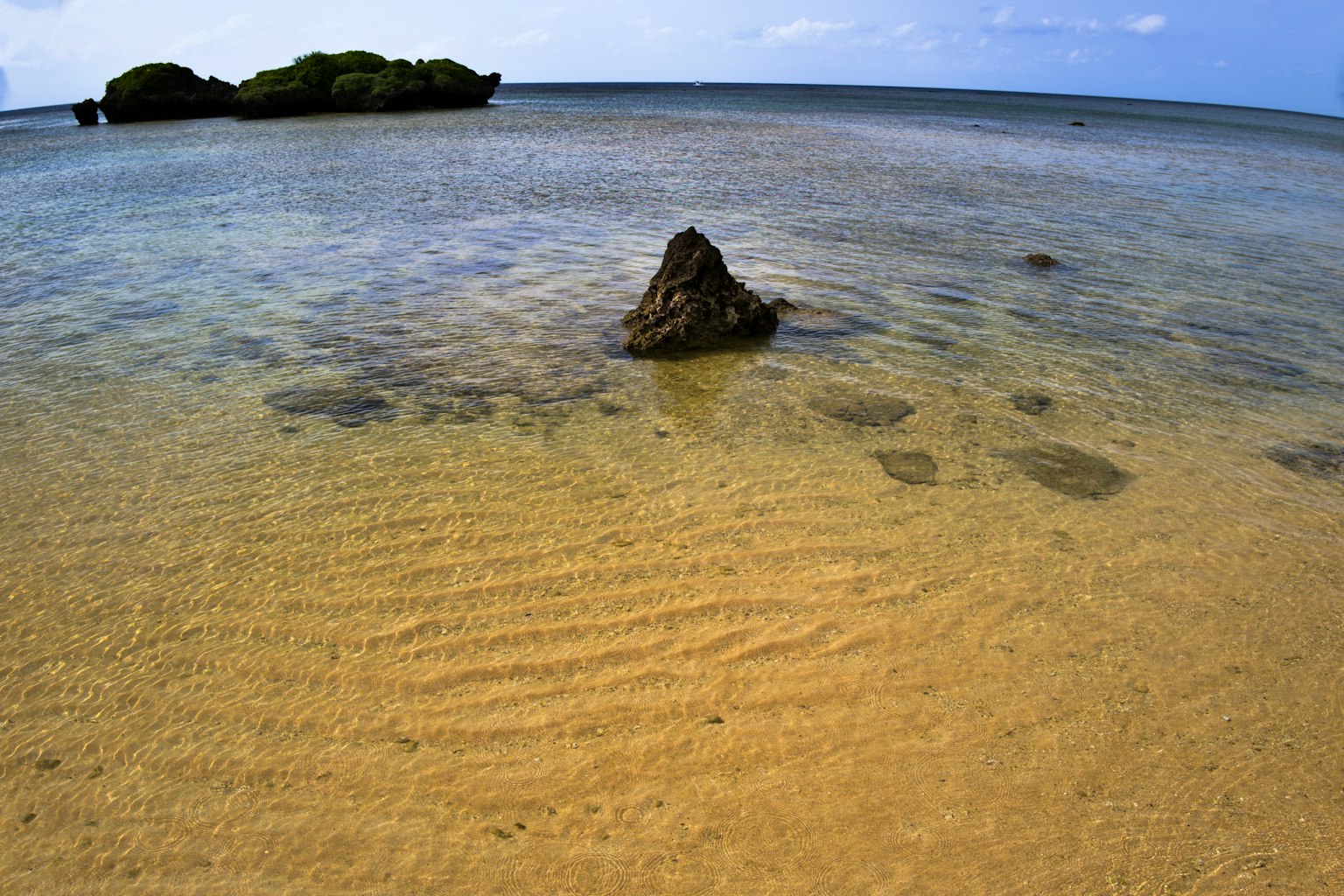 Pemandangan indah laut biru dan pantai berpasir dengan batu kecil