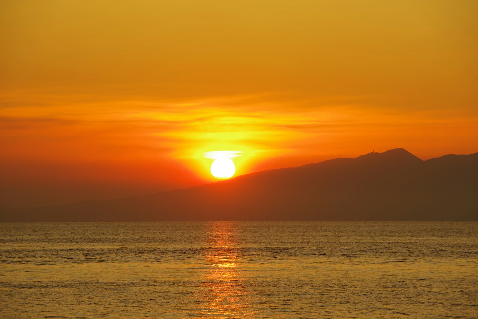 Tramonto sul mare con montagne sullo sfondo