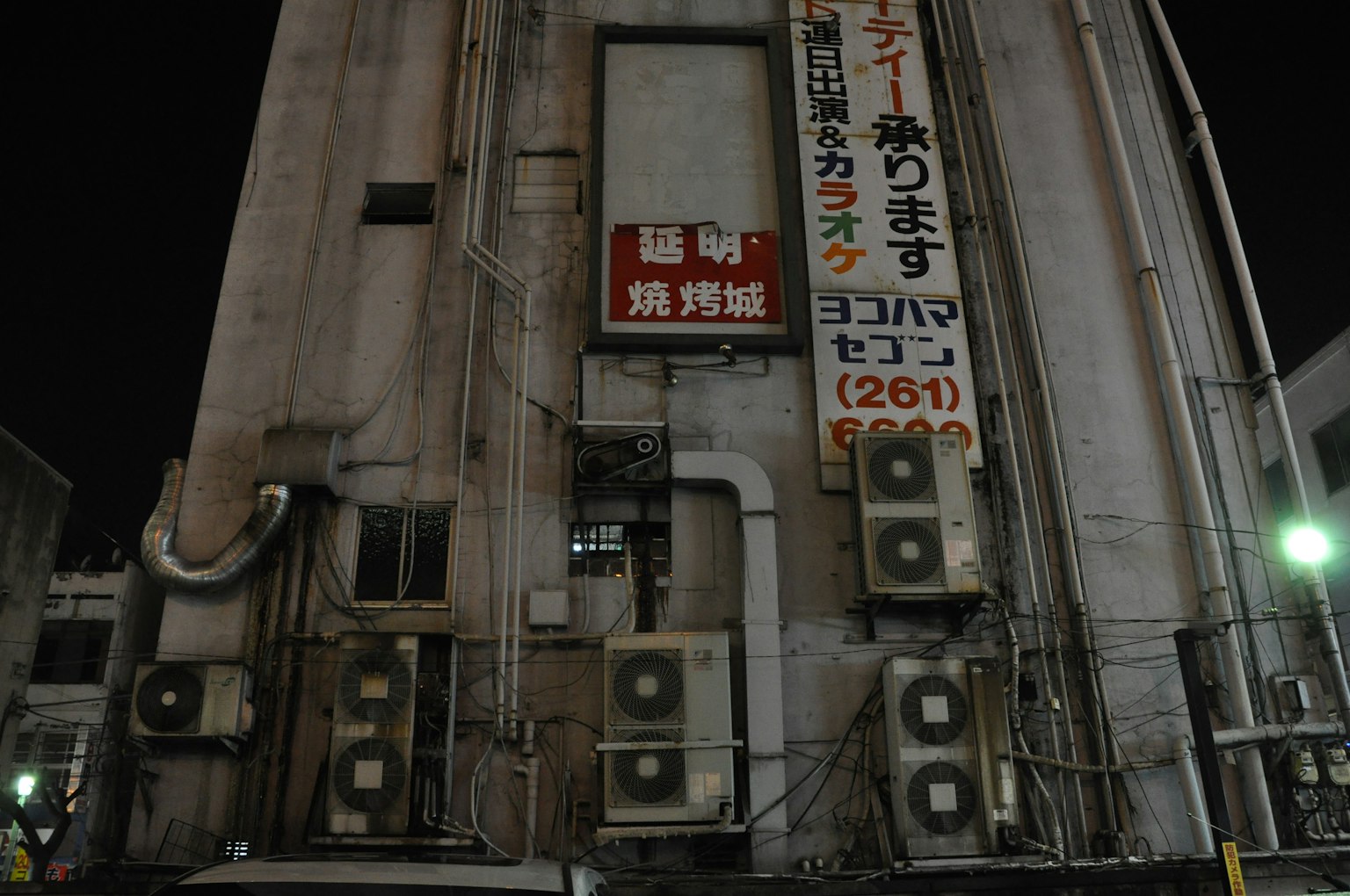 夜间建筑外墙上有多个空调和标志