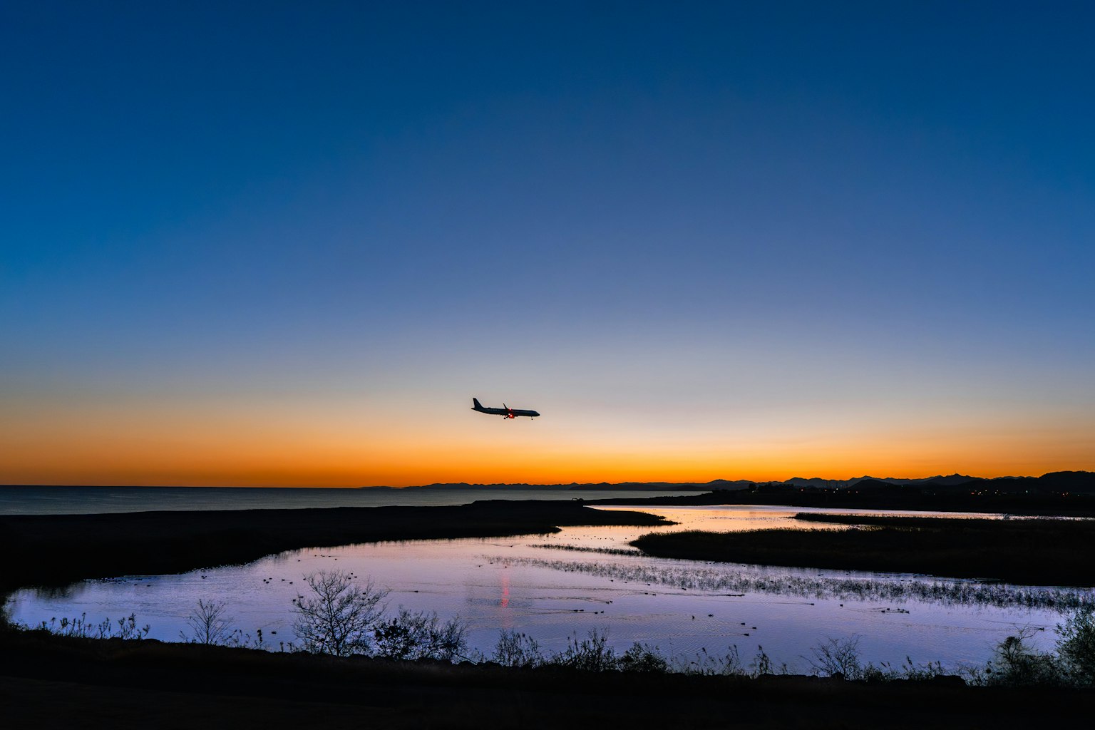 Bild eines Flugzeugs, das gegen einen Sonnenuntergangshimmel fliegt