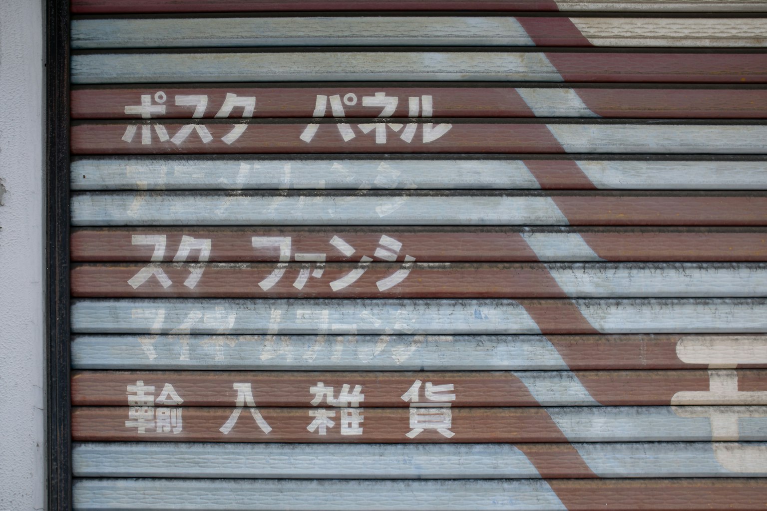 Texto japonés y patrones geométricos en una persiana