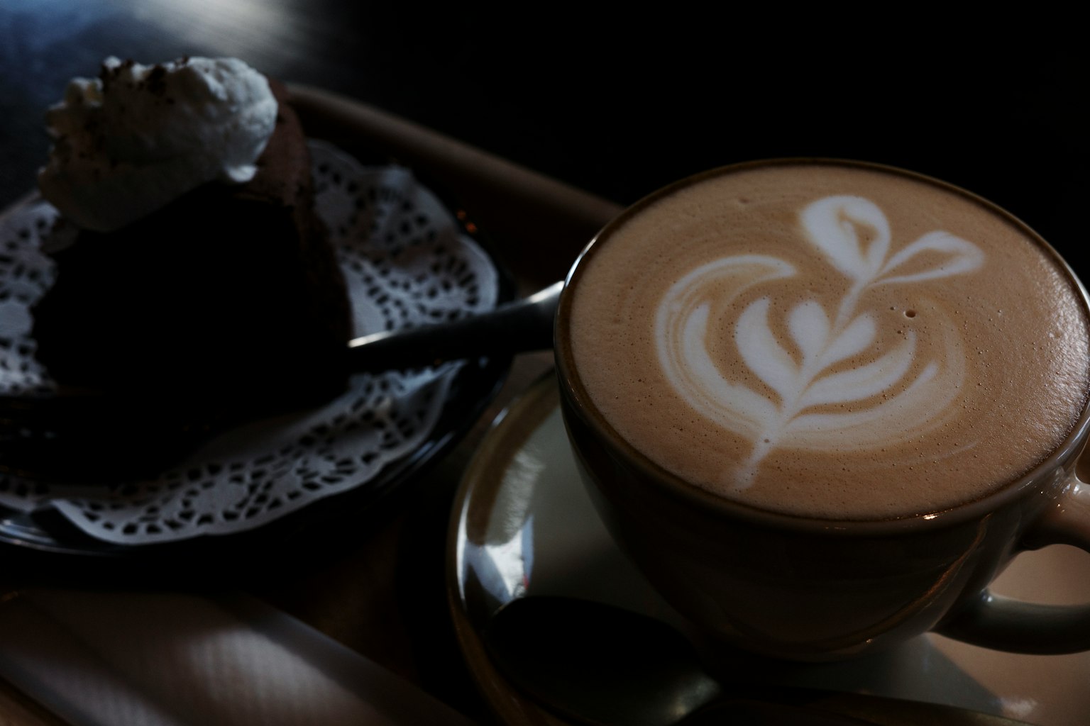 コーヒーとケーキの美しいプレゼンテーション ラテアートのデザインが特徴