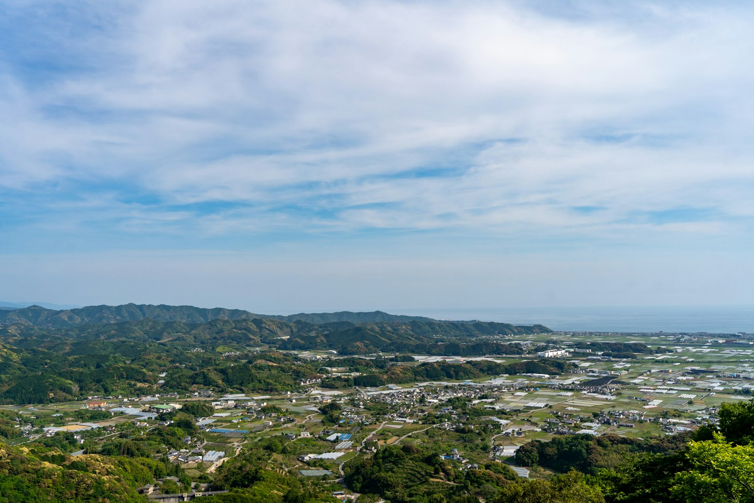 青い空の下に広がる緑の丘と海の景色