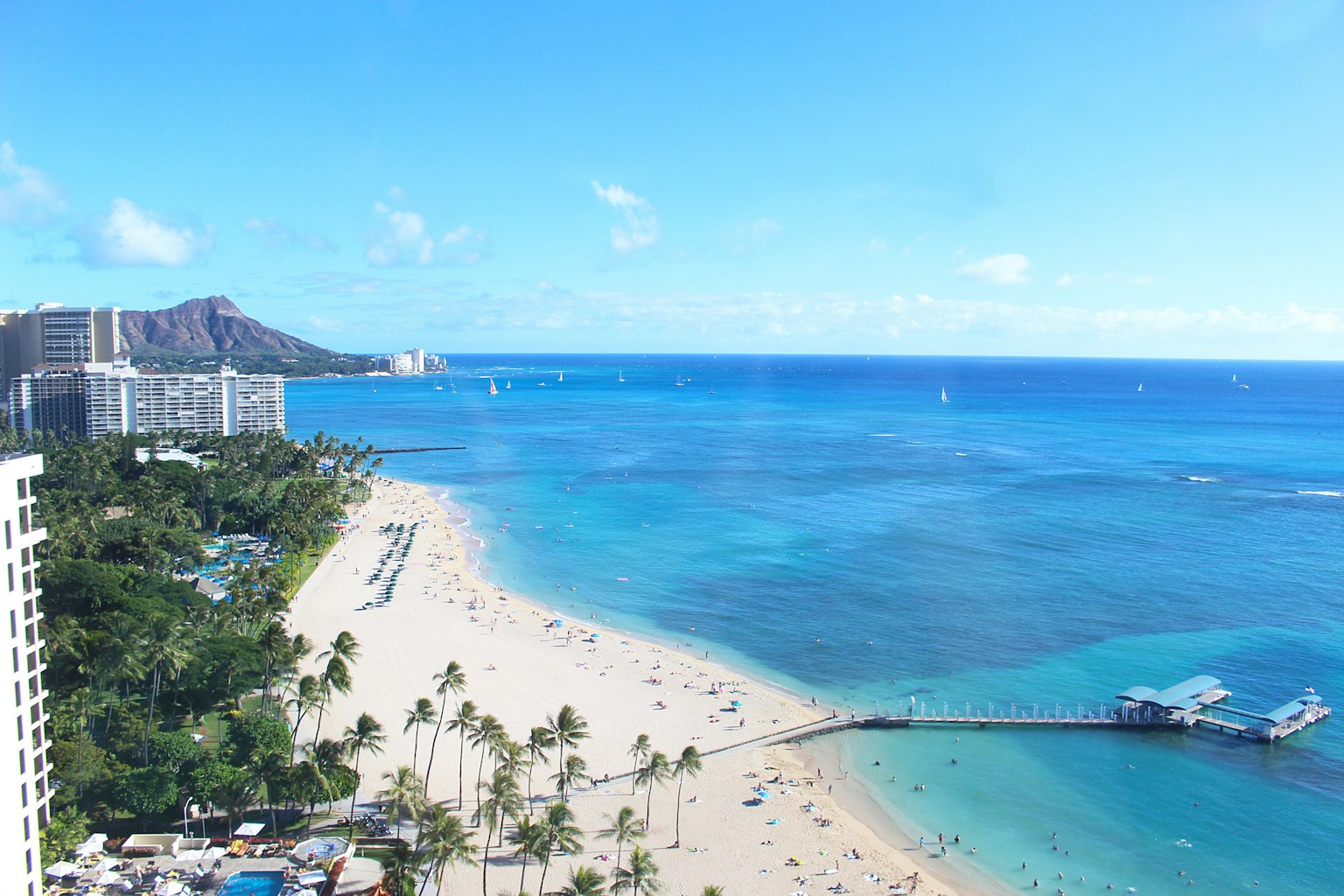 Panoramic view of a Hawaiian beach featuring blue ocean and white sand