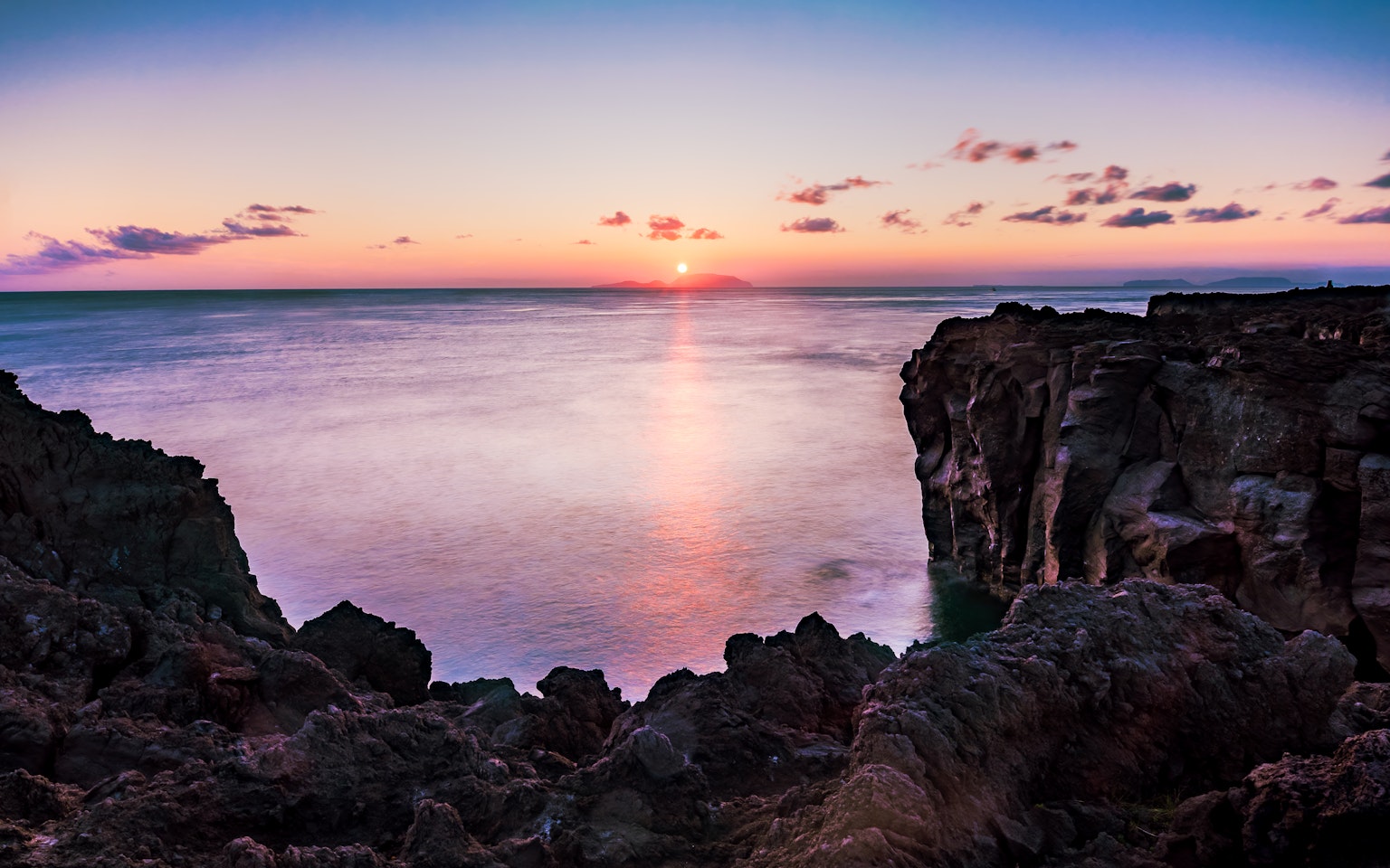 Stupendo tramonto sull'oceano calmo con costa rocciosa