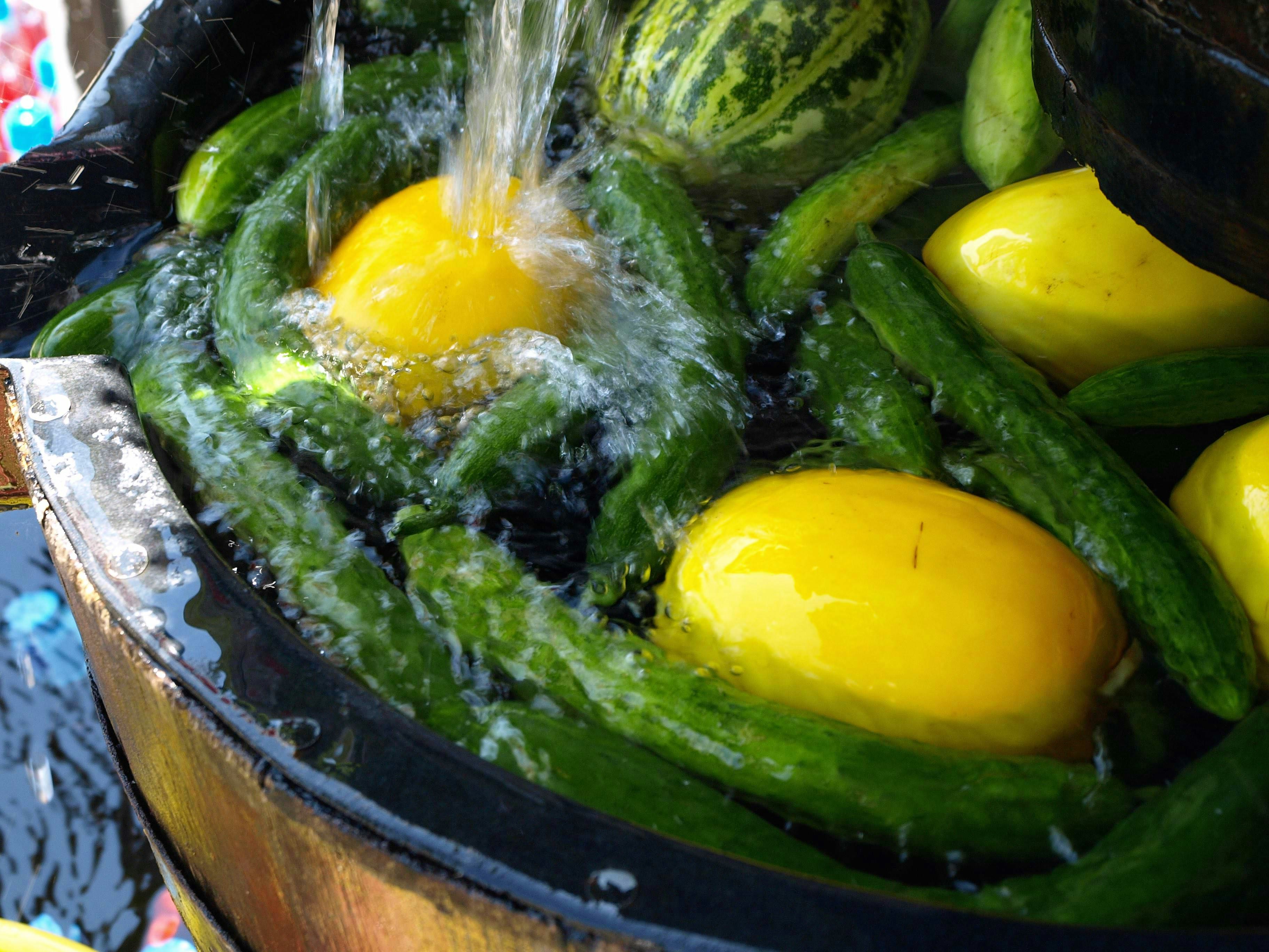 Close-up of a pot with green vegetables and yellow eggs splashing with water