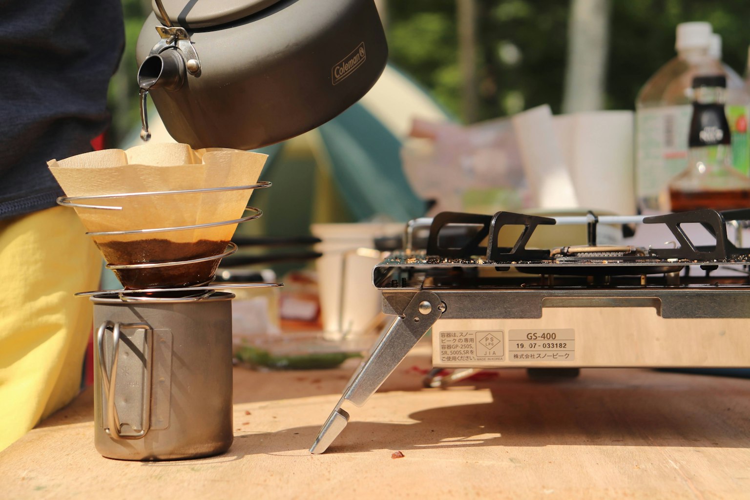 Szene mit Kaffeezubereitung am Campingplatz ein Metallkessel gießt in einen Filter
