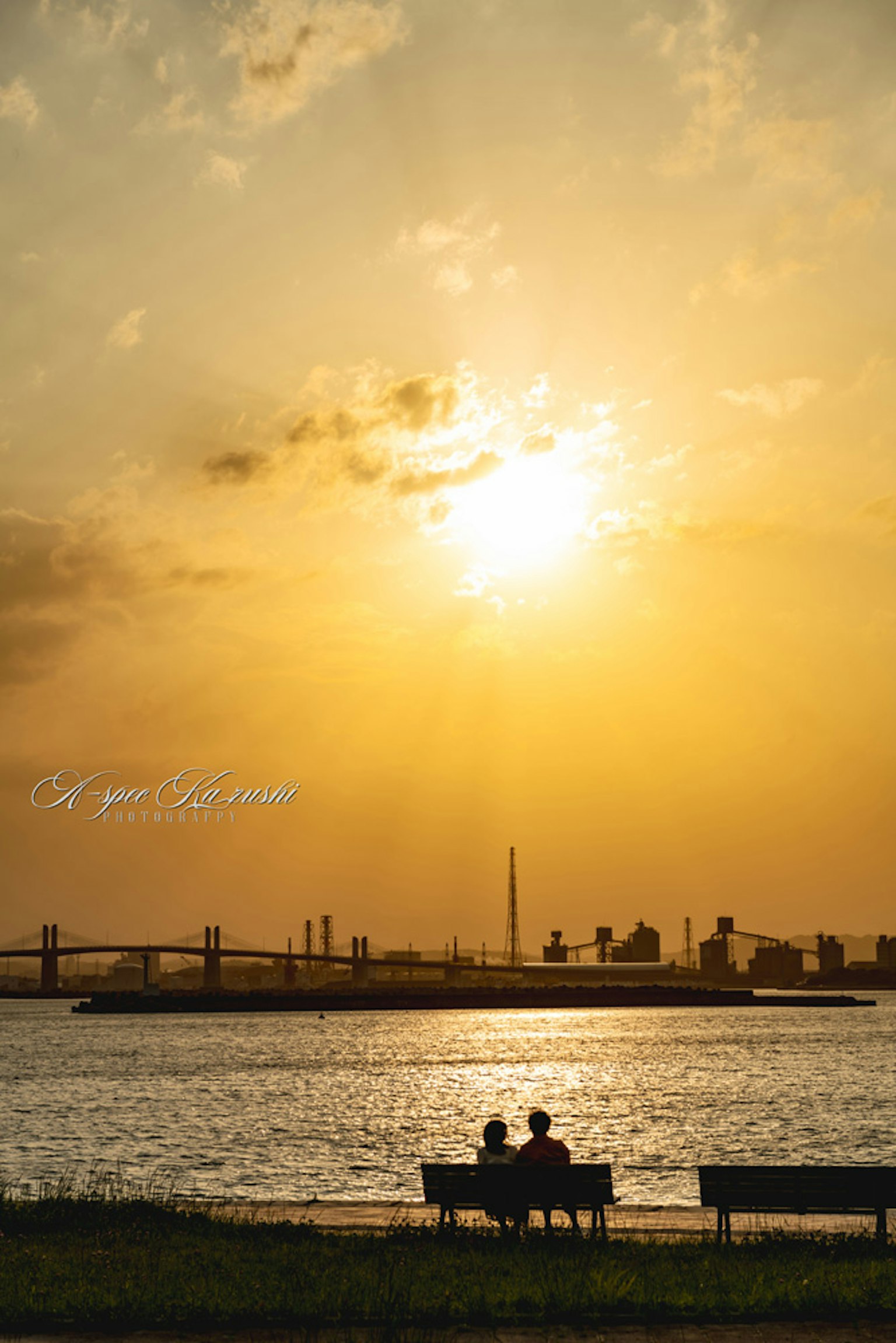 Pareja sentada en un banco mirando la puesta de sol sobre el río