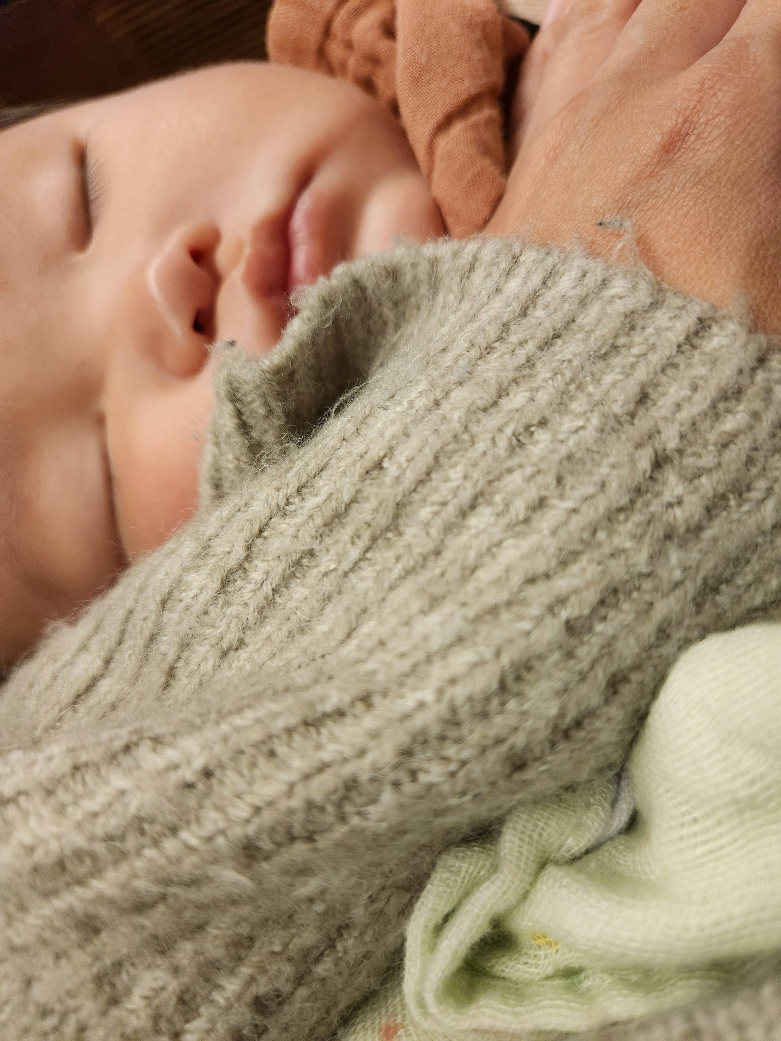 A sleeping baby wrapped in a large sweater sleeve