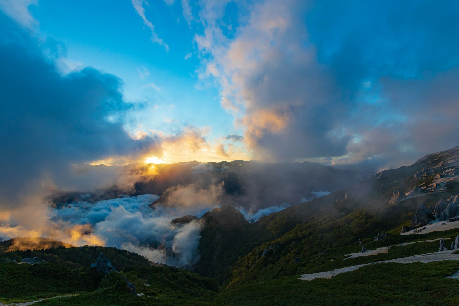 Impresionante paisaje de nubes y sol naciente entre montañas