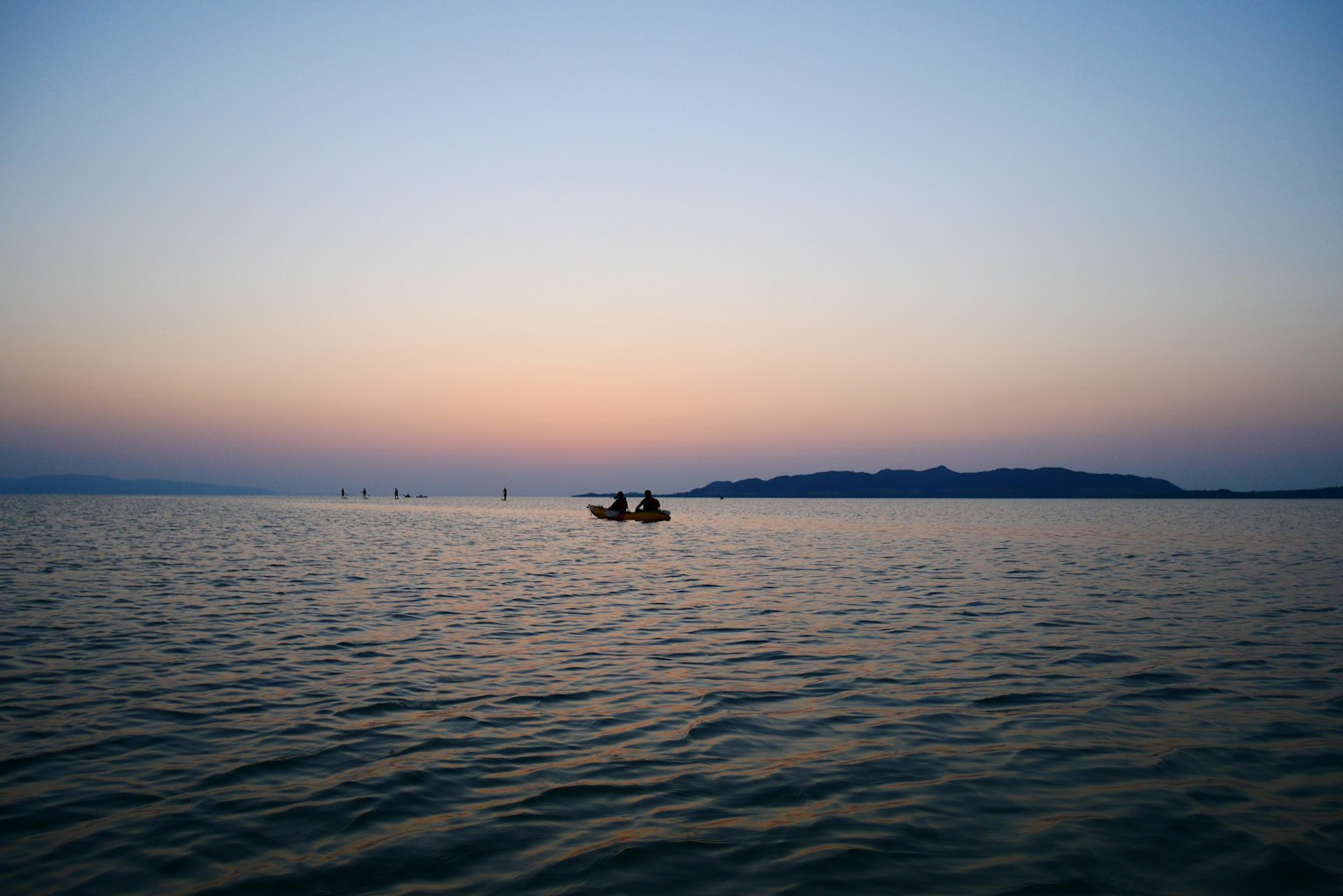 Small boat on calm sea at sunset with distant island