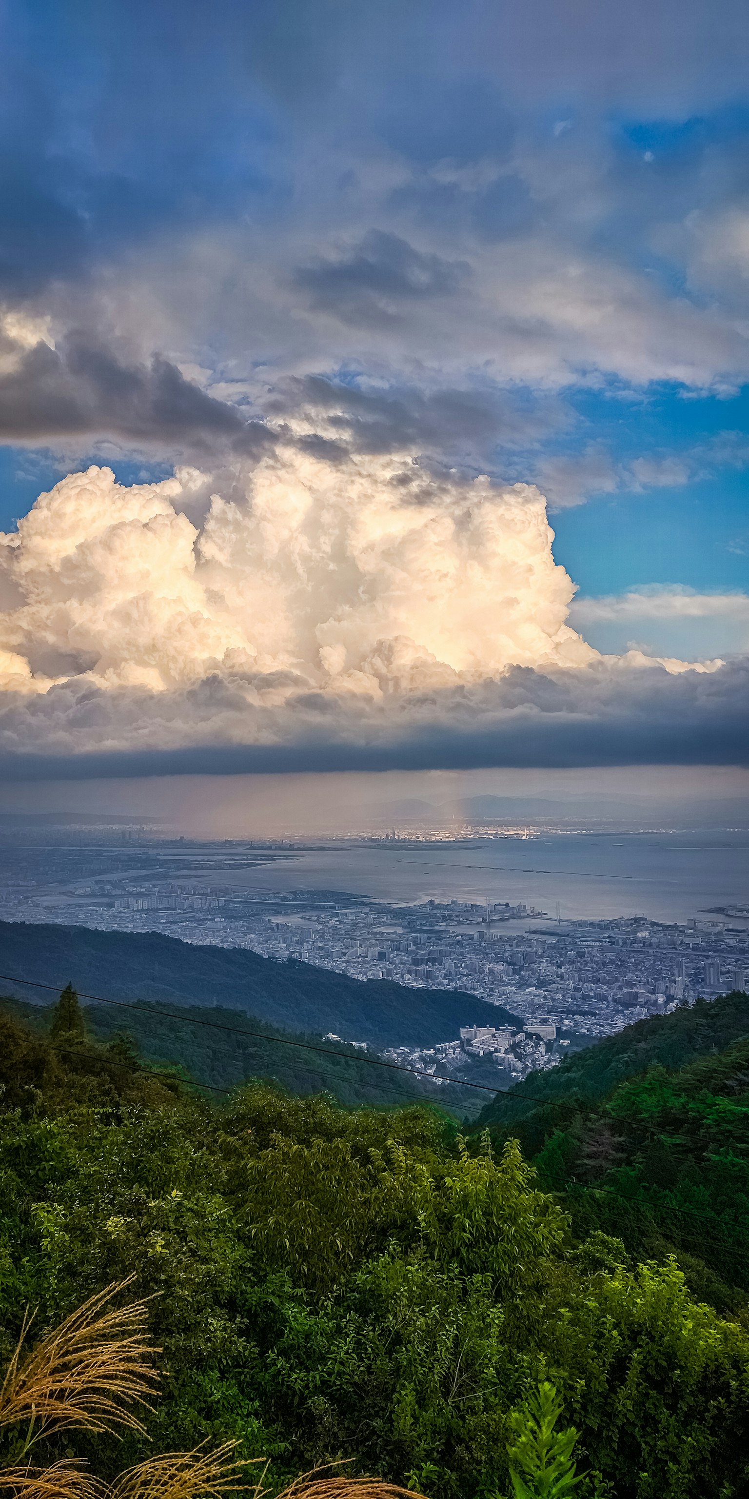 Mountain view overlooking a city by the sea under a cloudy sky