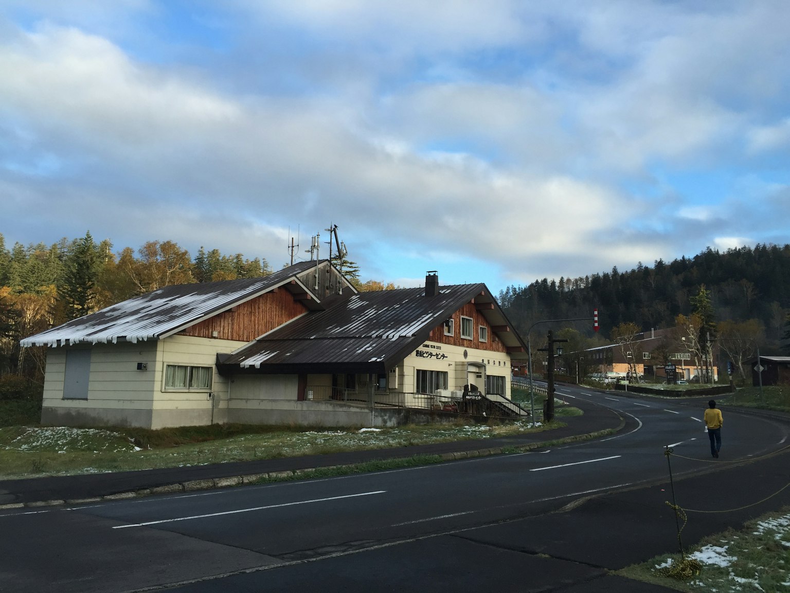 Haus an einer verschneiten Straße mit Herbstbäumen im Hintergrund