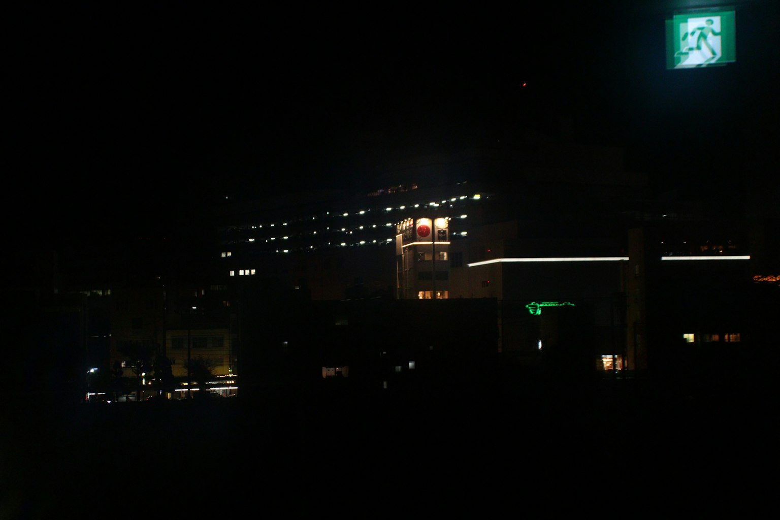Hôtel illuminé la nuit avec enseigne verte dans le paysage urbain