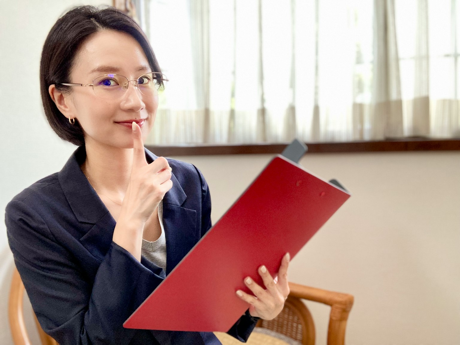 Người phụ nữ cầm tập tài liệu màu đỏ với biểu cảm suy tư