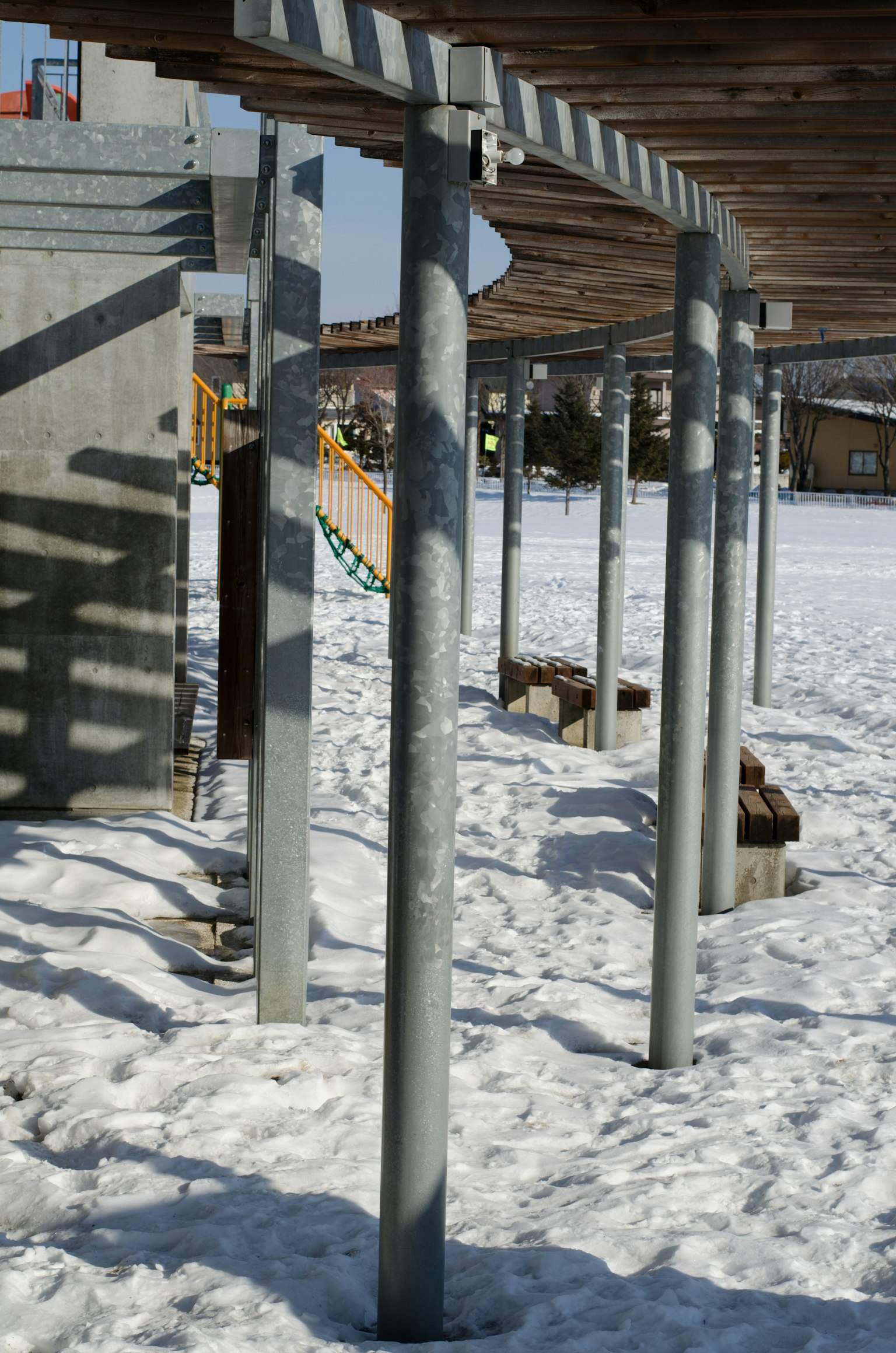 Metallsäulen auf schneebedecktem Boden mit Holzstruktur