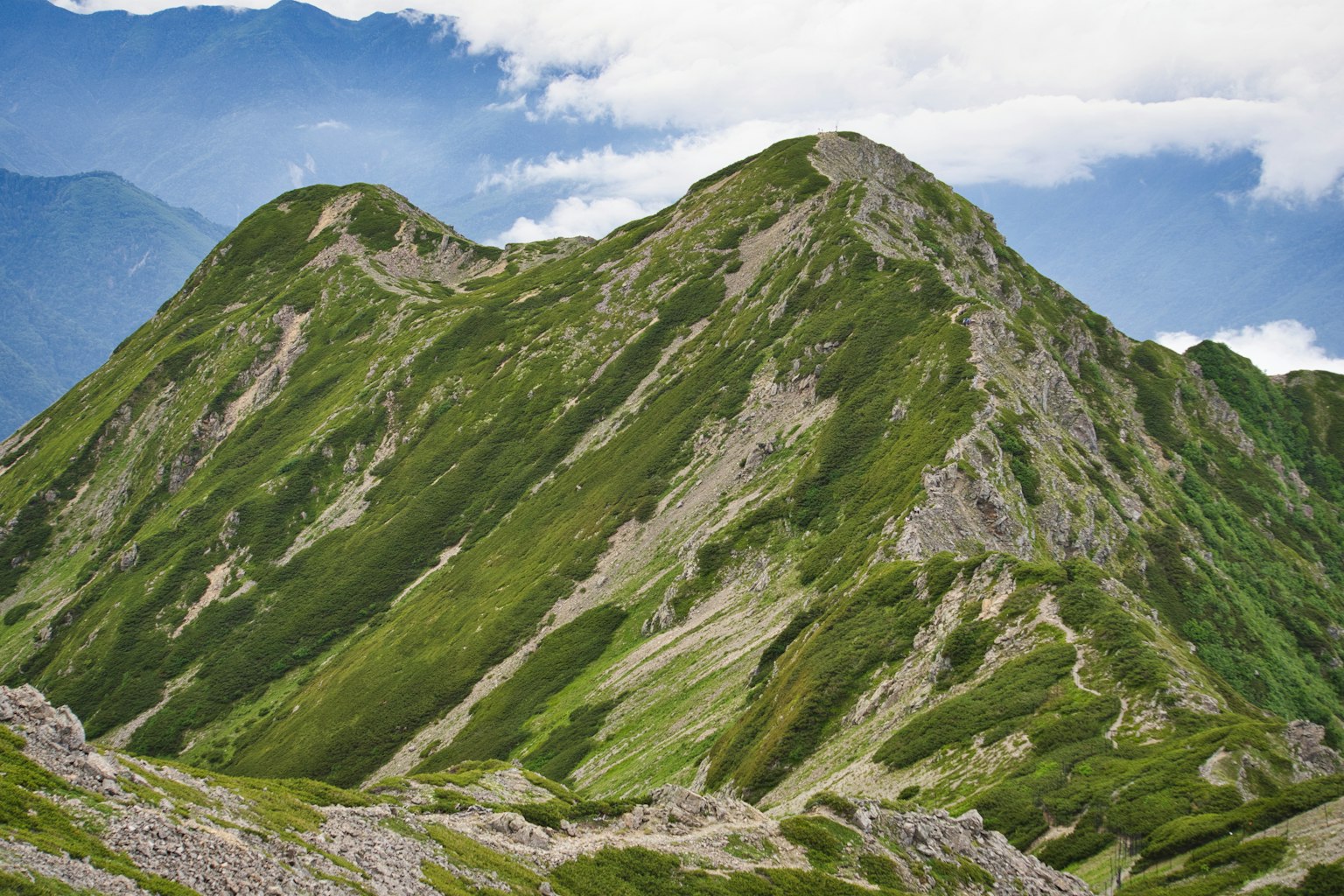 Paesaggio montano verdeggiante con cime ondulate