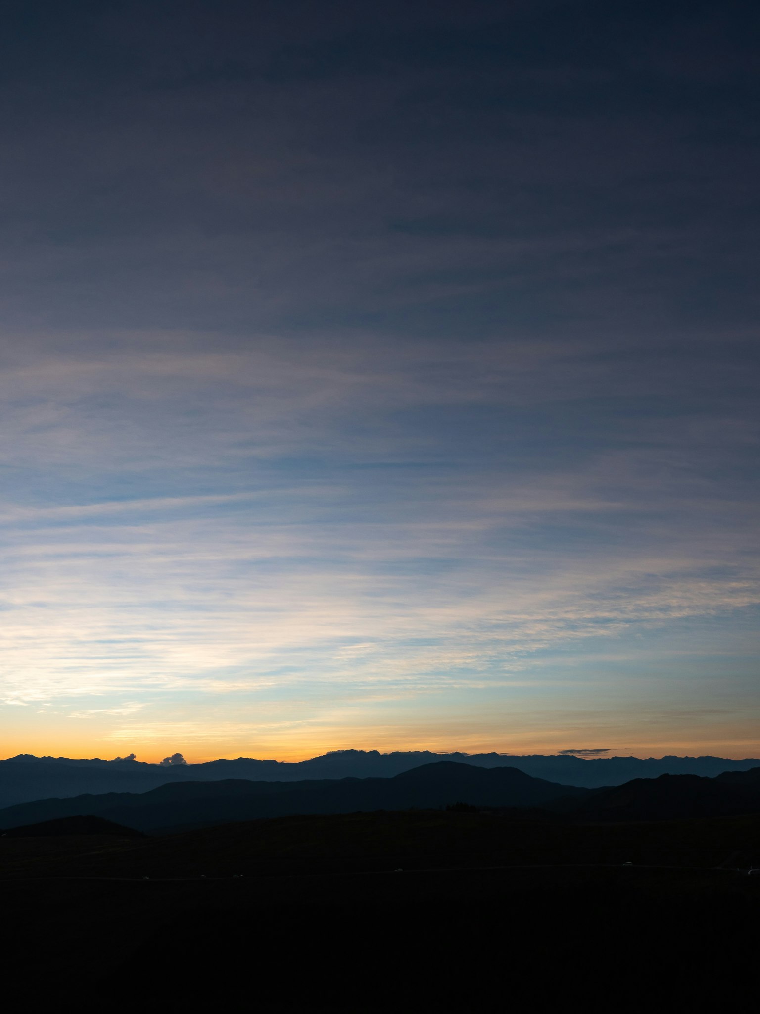 Gradient sky with blue and orange hues and silhouetted mountains