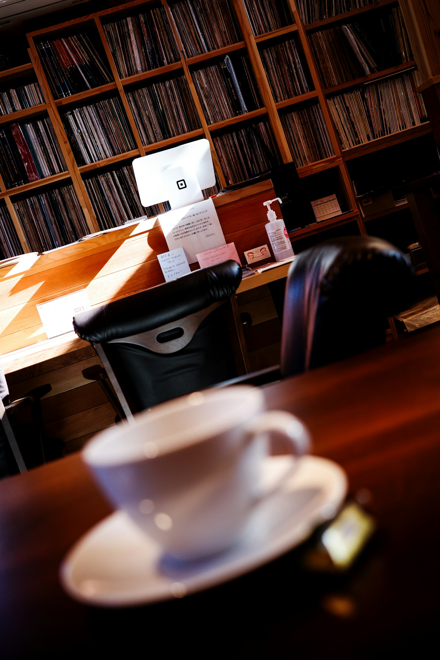 Tasse de café blanche sur une table en bois avec une bibliothèque en arrière-plan