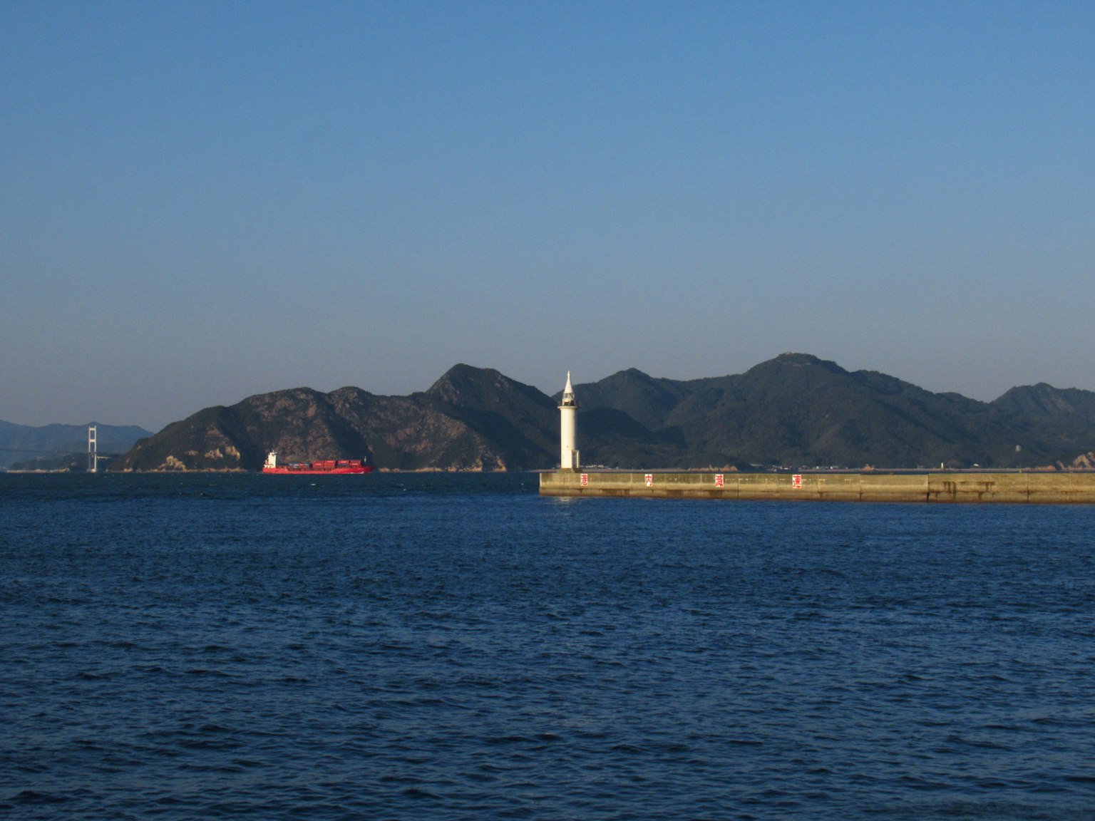 Vista escénica del mar con un faro y un barco pasando