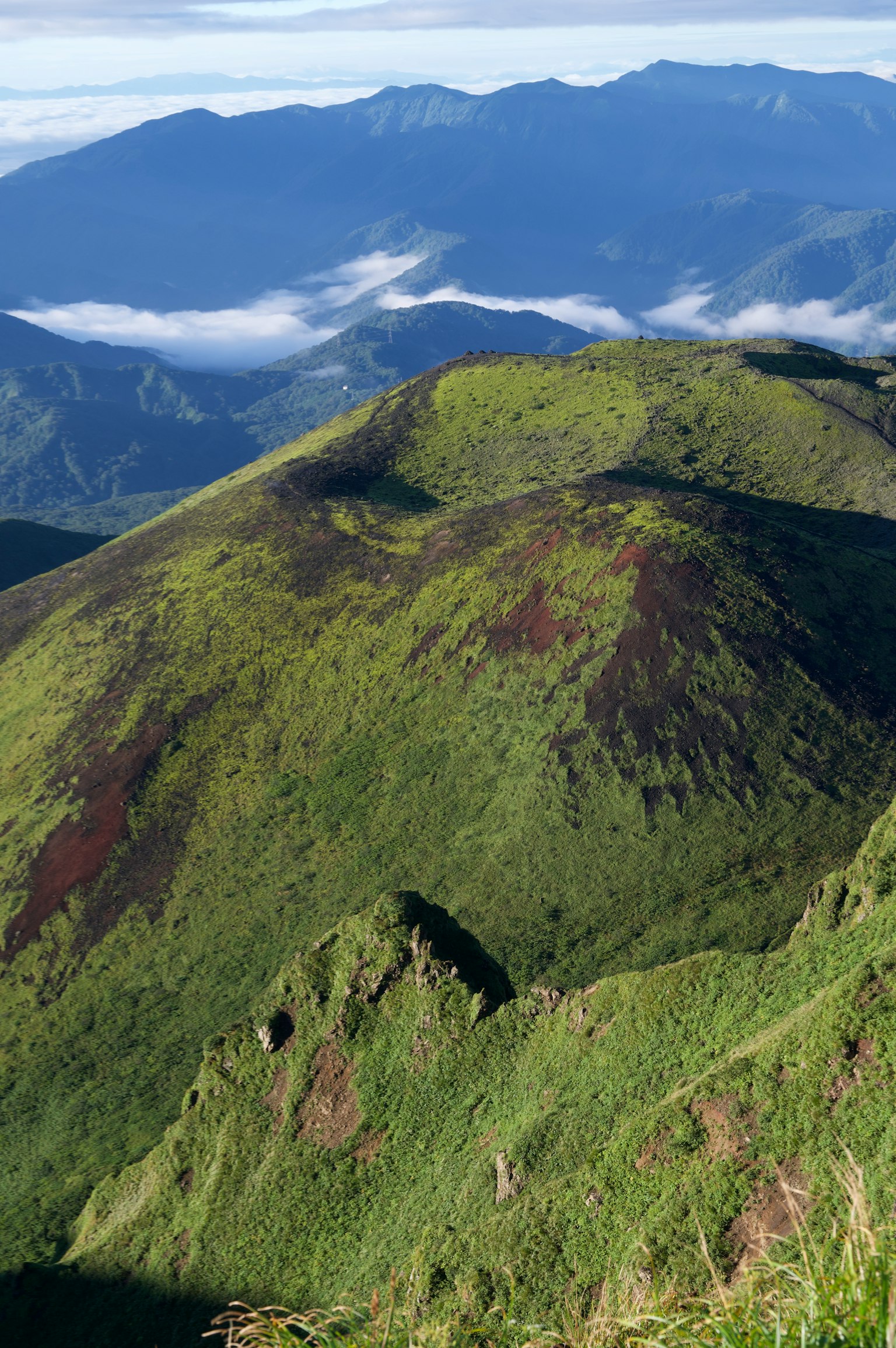 Paisaje montañoso verde con picos distantes