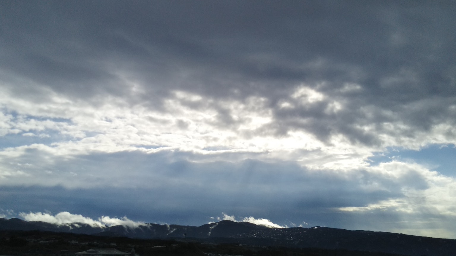 Paysage montagneux dramatique avec contraste entre nuages sombres et ciel bleu