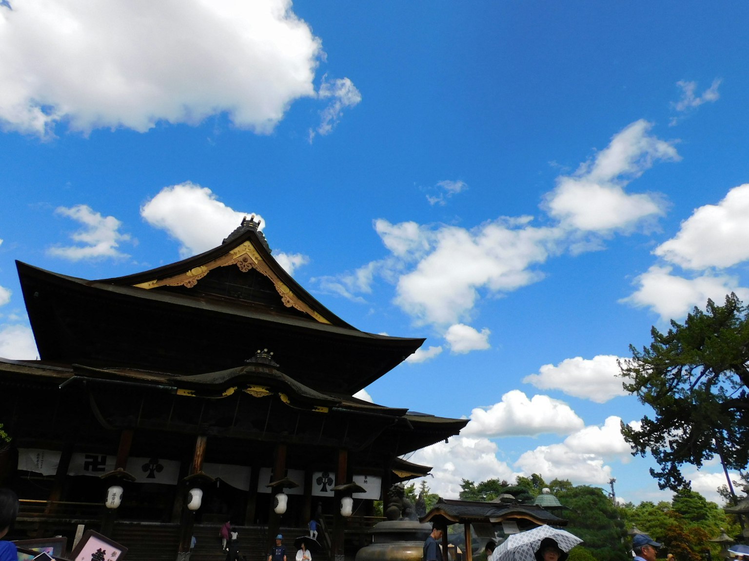 Traditional Japanese temple roof under a bright blue sky with white clouds