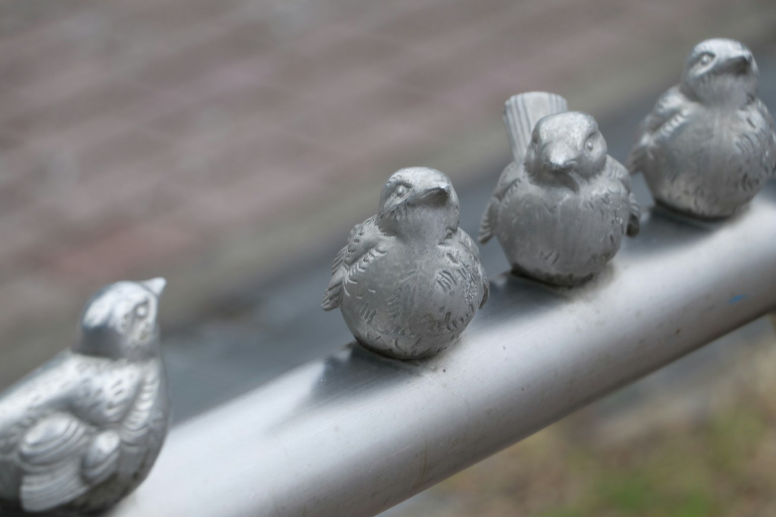 Vier silberne Vogelskulpturen auf einem Geländer aufgereiht