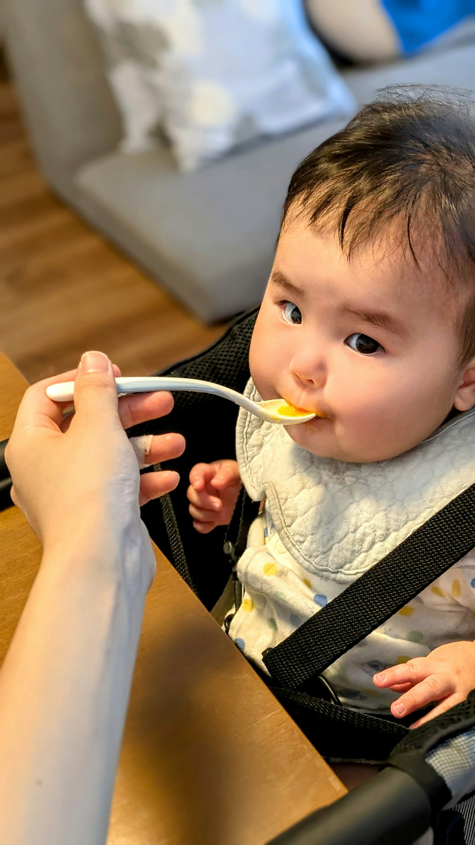 Bambino che mangia con un cucchiaio da un caregiver